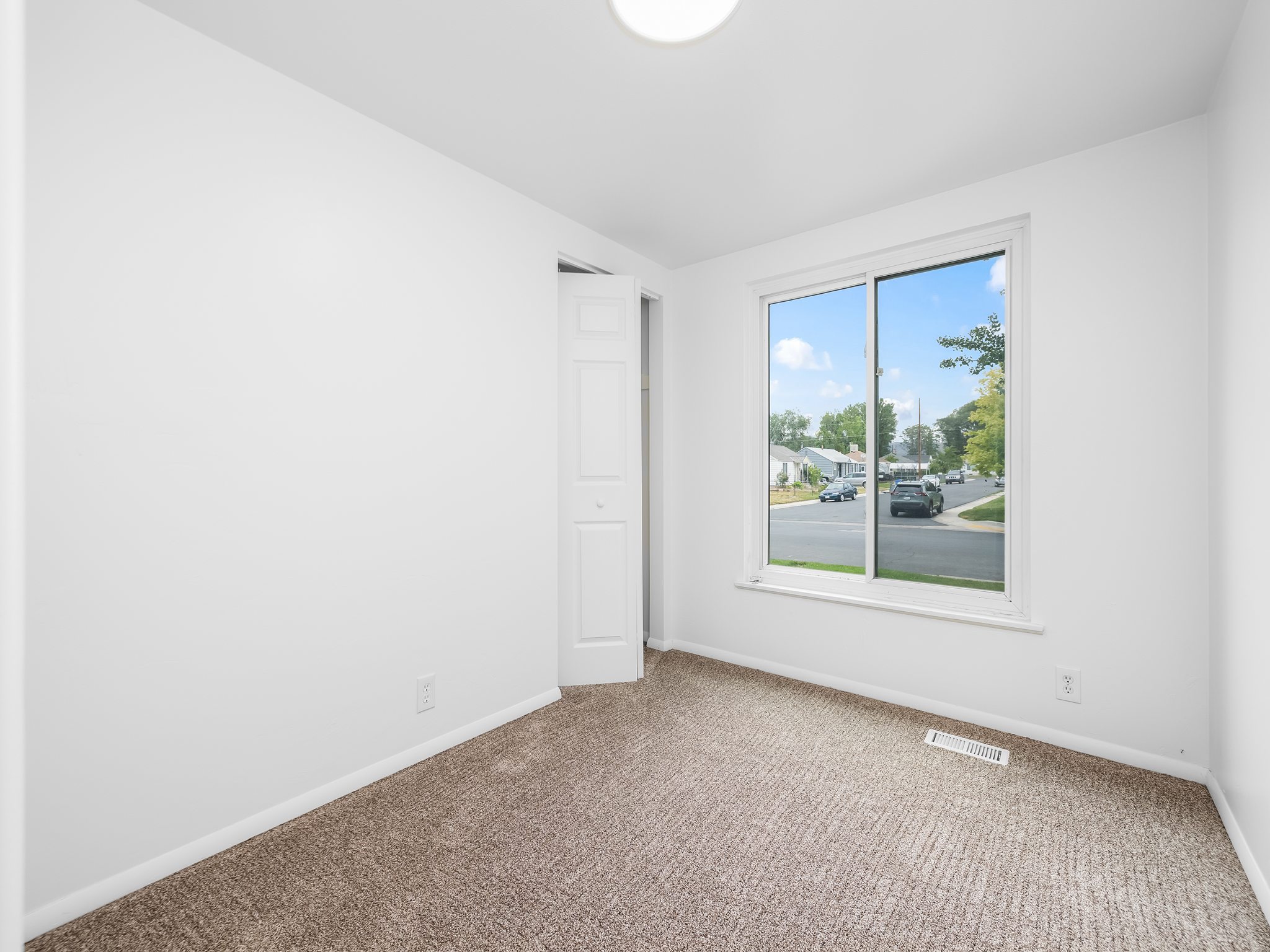 Bright room with neutral wall paint and textured carpet flooring