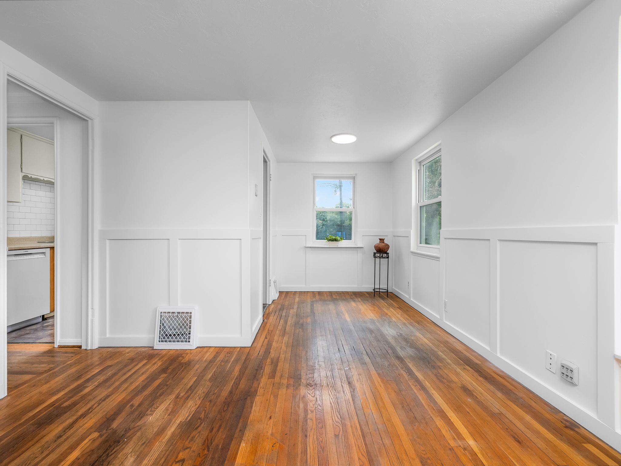 Hardwood flooring extending through the room, accented by white board and batten wall paneling