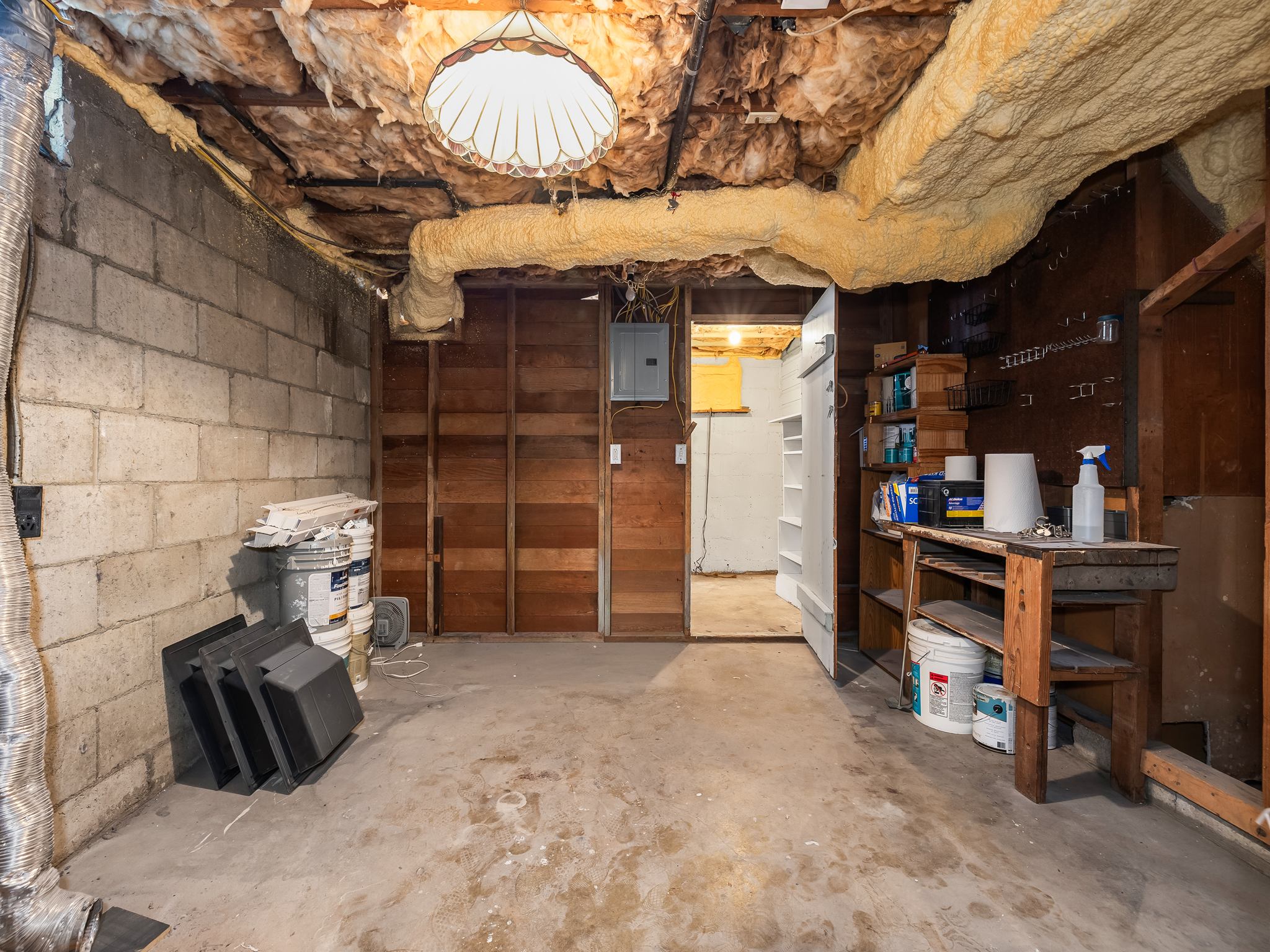 Unfinished basement featuring concrete block walls, exposed wood framing, and concrete flooring