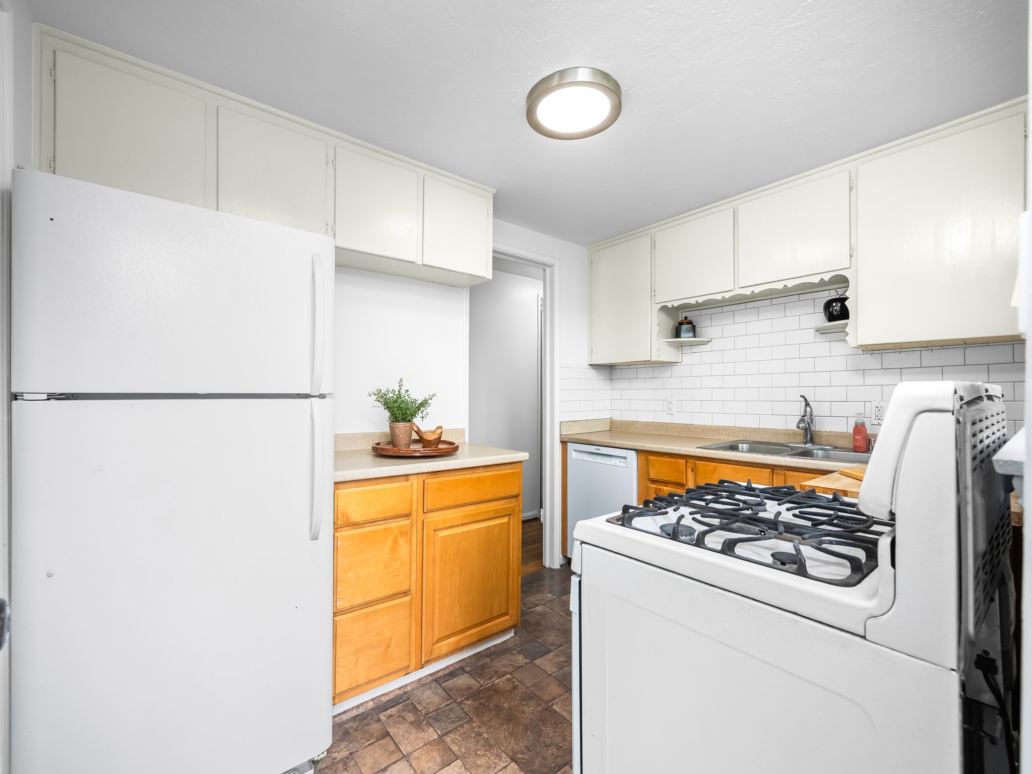 Kitchen featuring white cabinetry, light countertops, subway tile backsplash, and wood-finish lower cabinetry