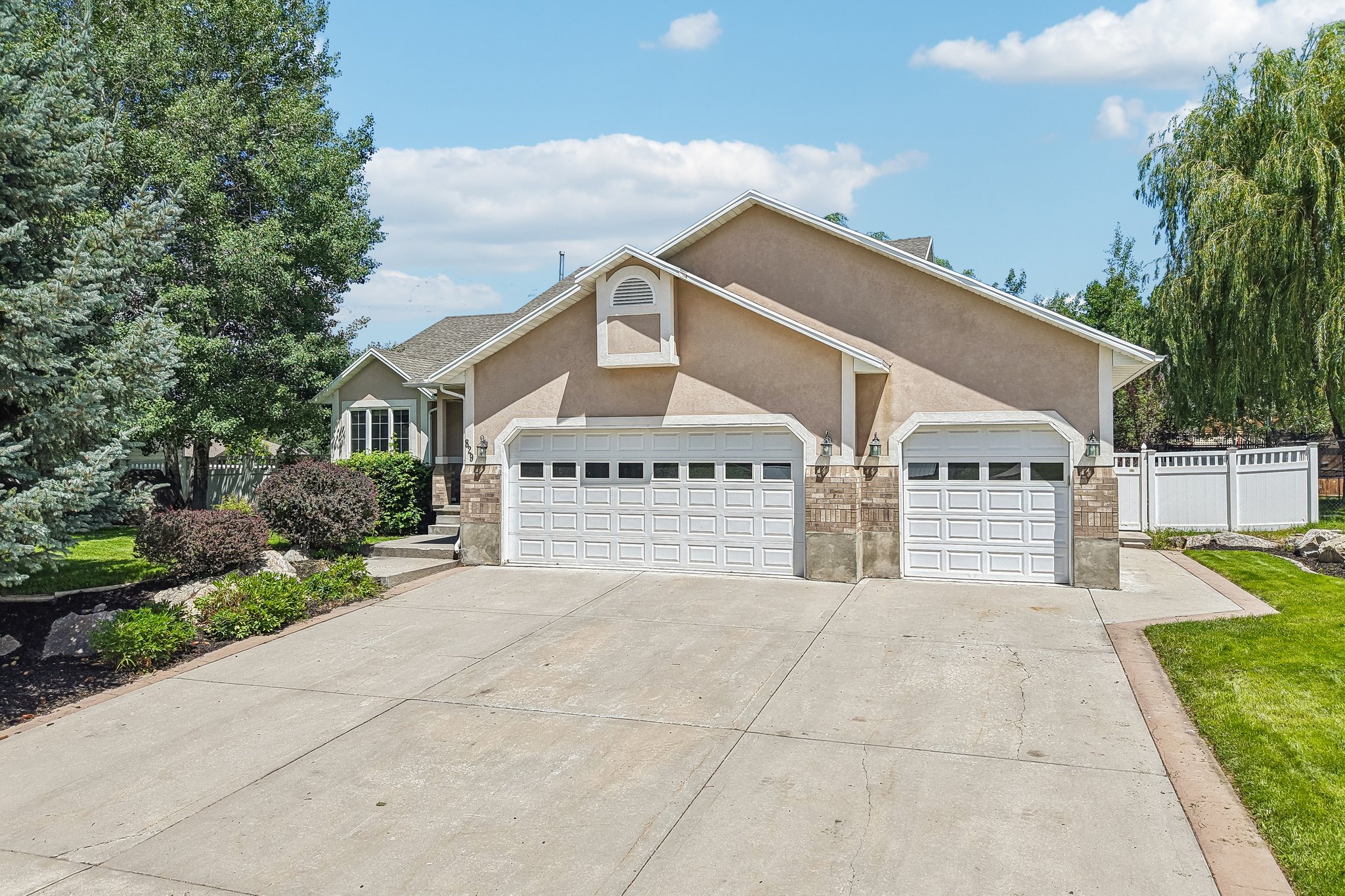 Exterior featuring a two-car garage with panel doors, stone accents, and stucco siding
