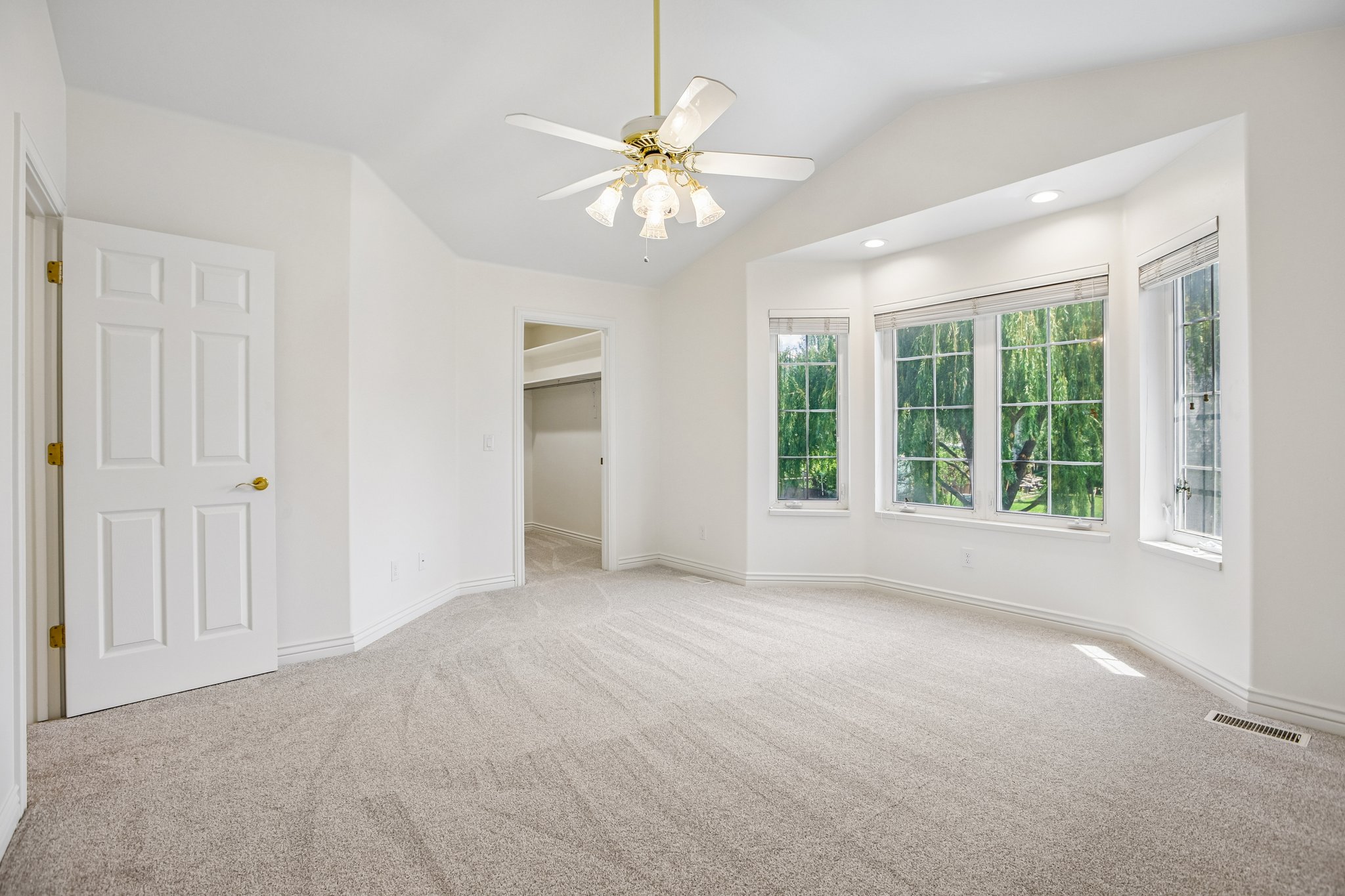 Bay window with multi-pane windows, vaulted ceiling, recessed lighting, ceiling fan, and light grey carpeting