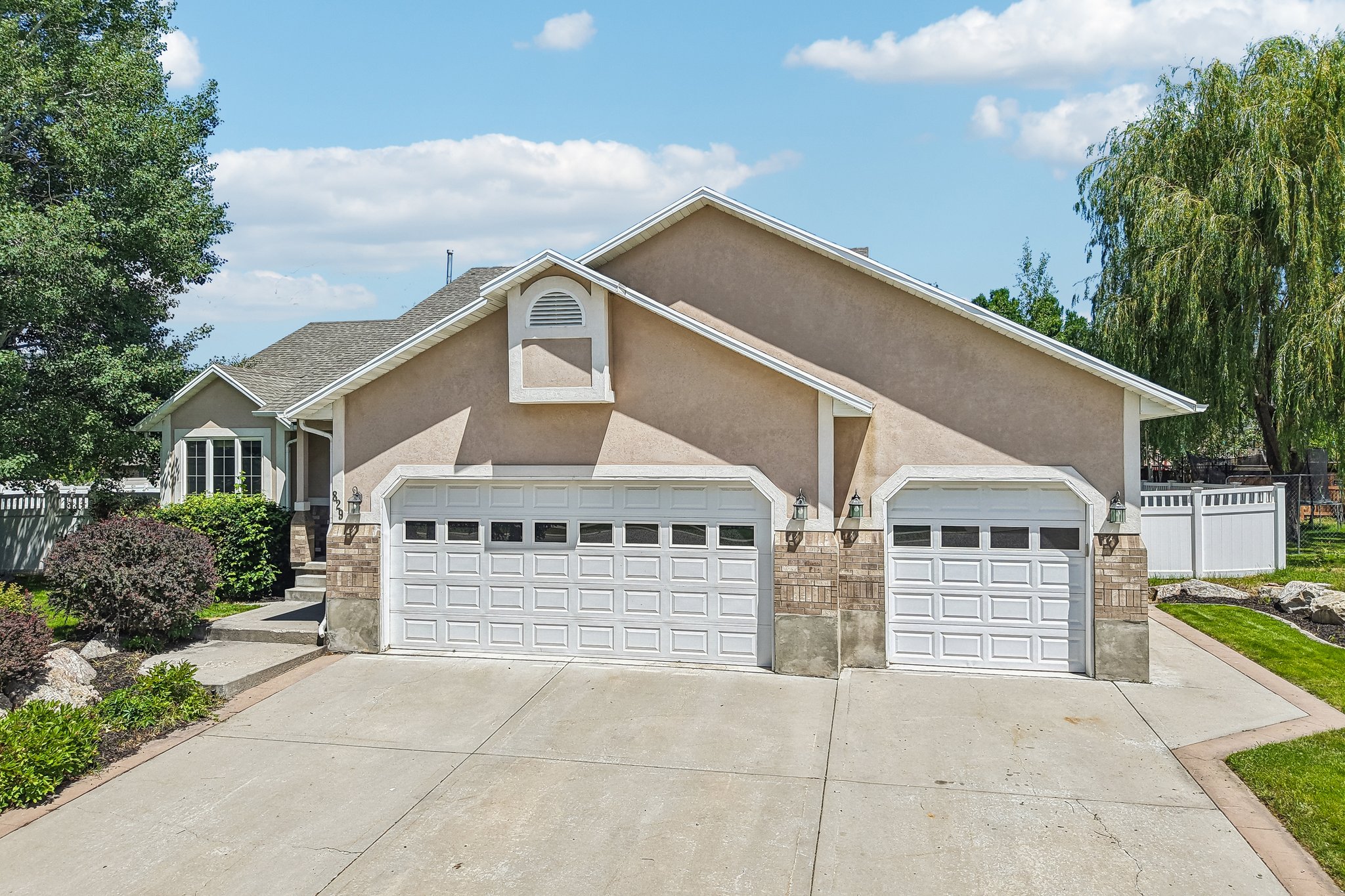Stucco exterior with a multi-car garage, brick accents, and concrete driveway