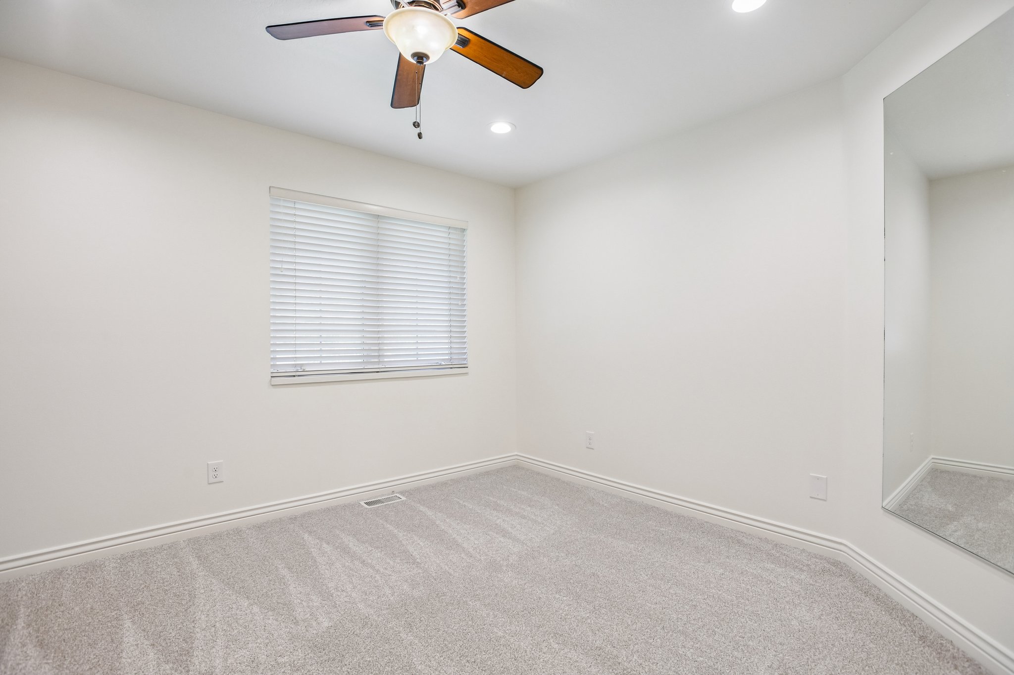 Room featuring light-toned carpeting, a window with horizontal blinds, and a ceiling fan with integrated lighting