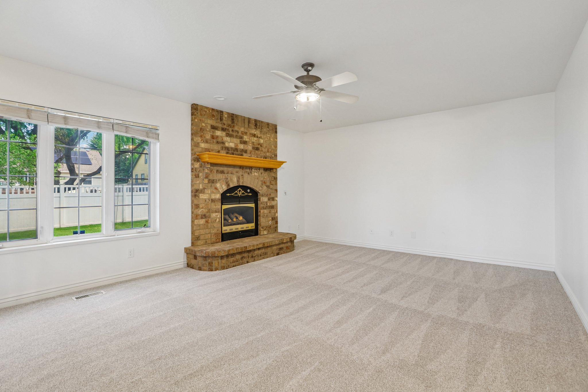 Carpeted living space featuring a brick fireplace with a wood mantle