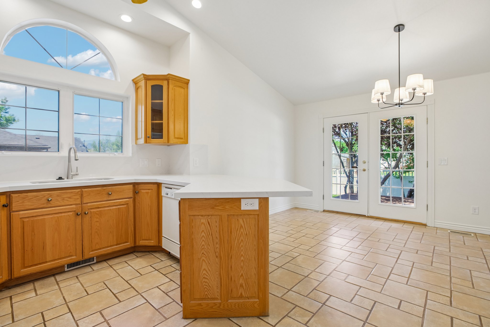 Kitchen area with light wood cabinetry, white countertops, and a white subway tile backsplash
