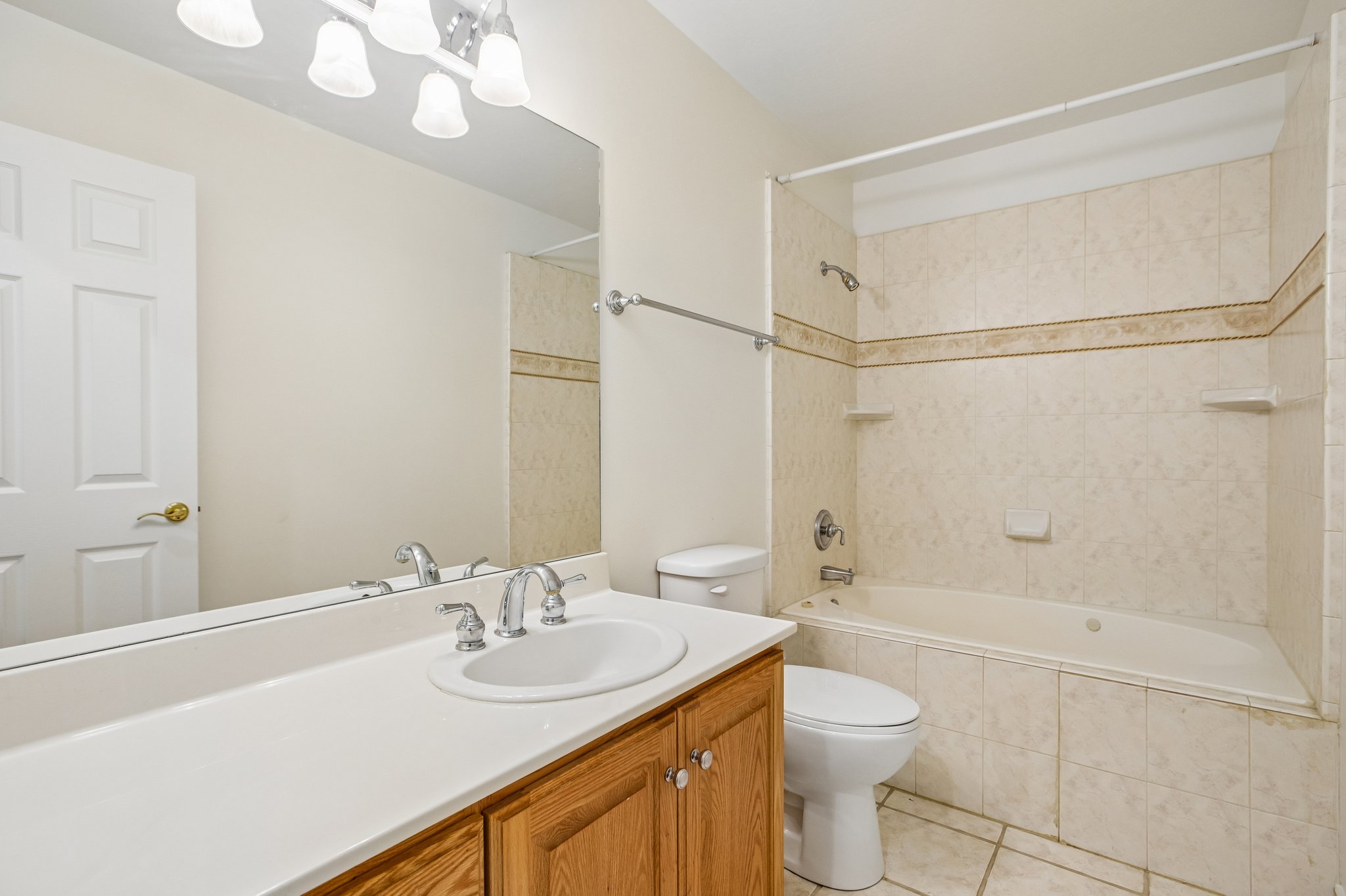 Spacious bathroom featuring a white countertop vanity with an integrated sink, a large wall-mounted mirror, and a wood-finish cabinet