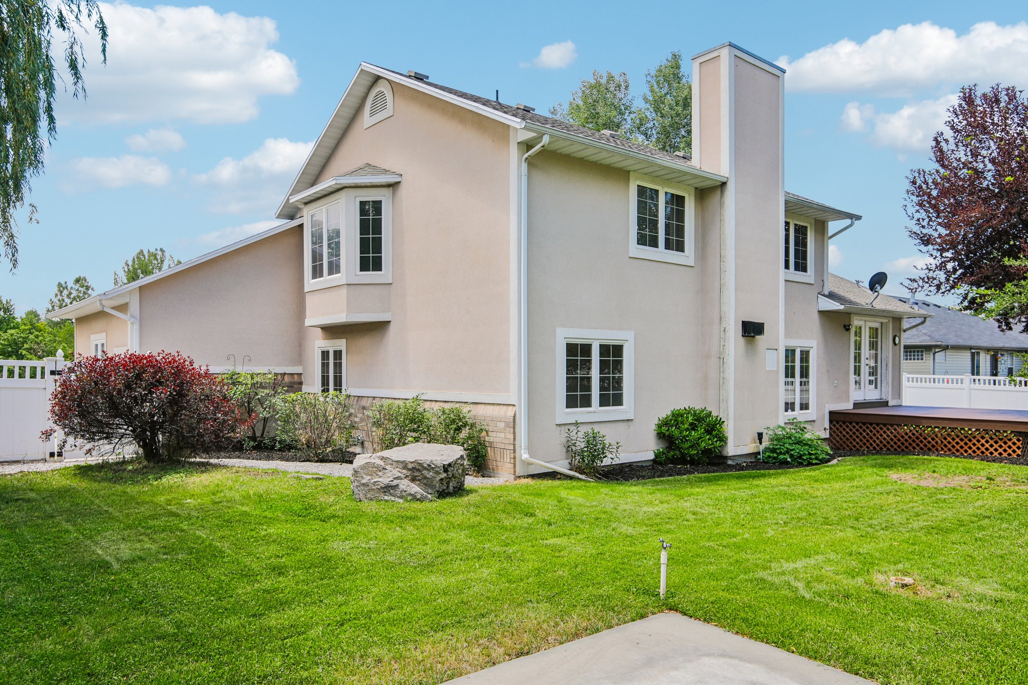 Stucco exterior featuring multiple windows, a bay window, and a prominent chimney