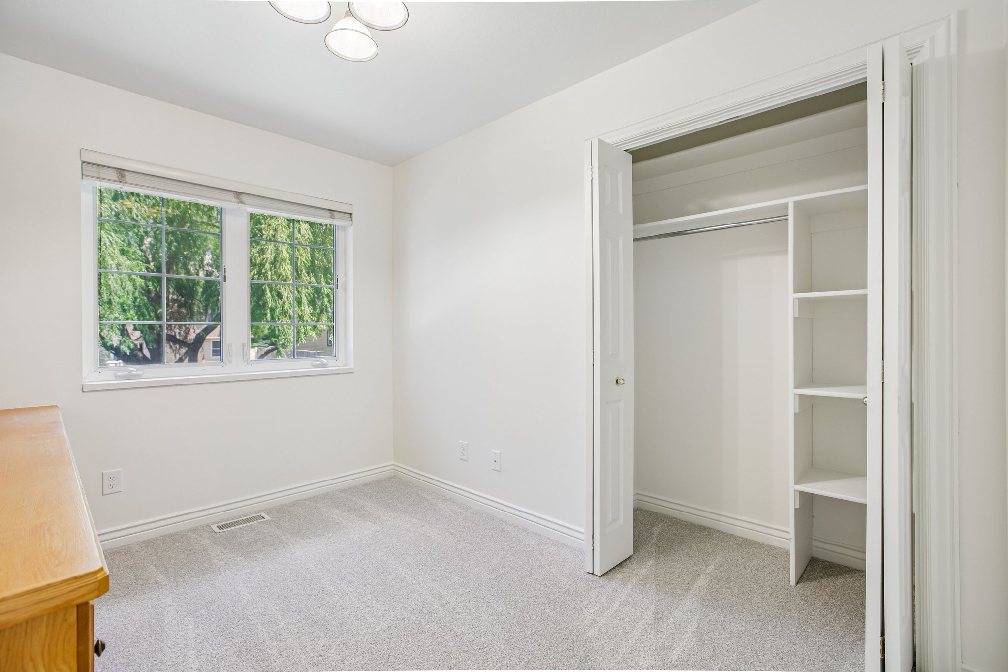 Bedroom featuring light-toned carpeting, a dual-pane window with white trim, and a ceiling-mounted light fixture
