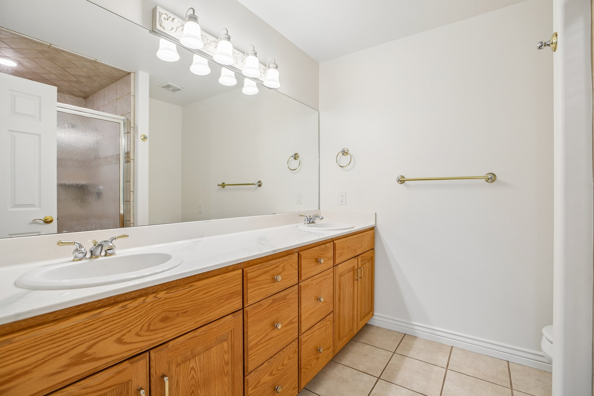 Dual vanity featuring wood-finish cabinetry and white countertops