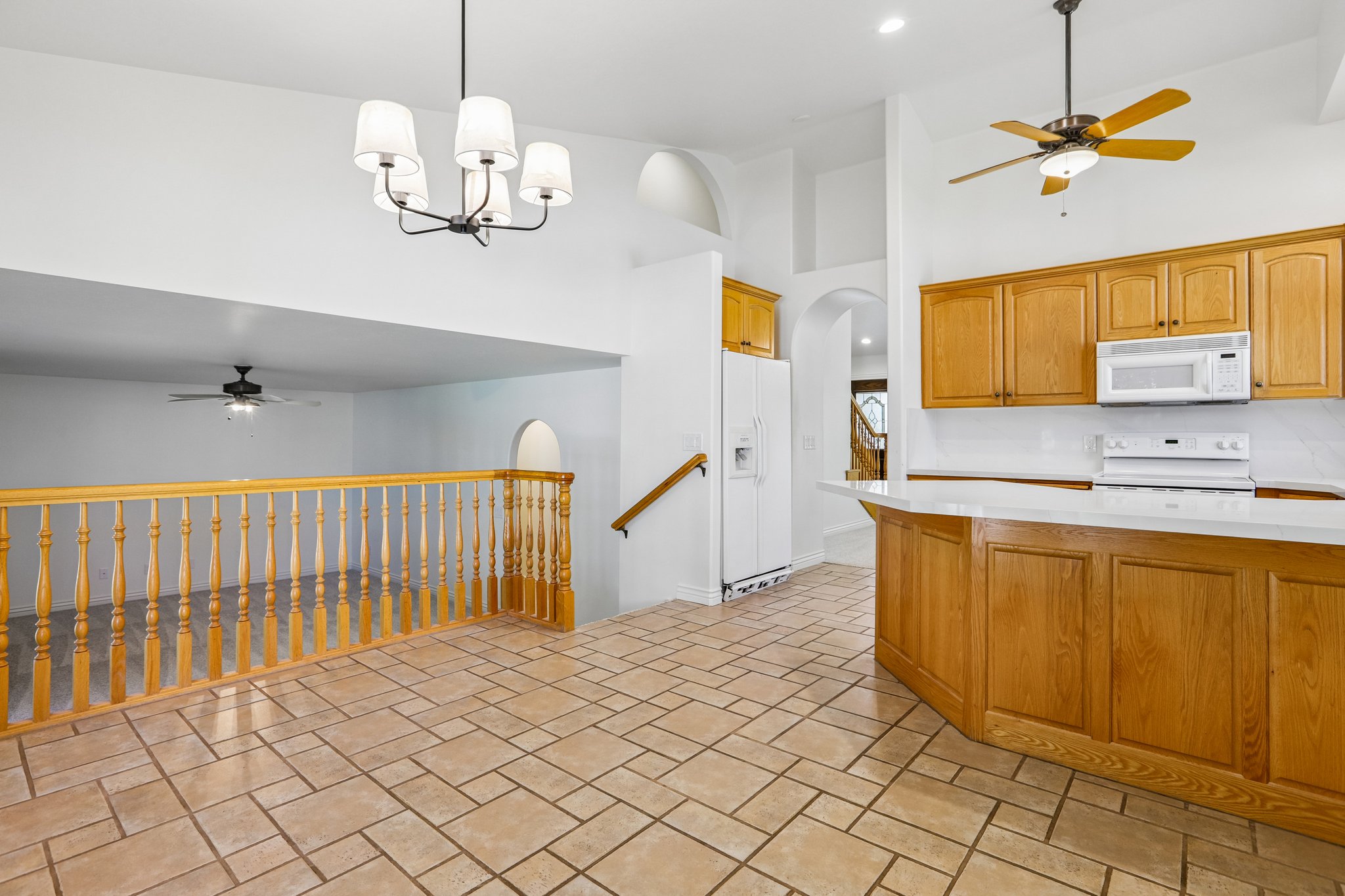 Open-concept kitchen and living area featuring tile flooring, oak cabinetry, white countertops, and a white tile backsplash