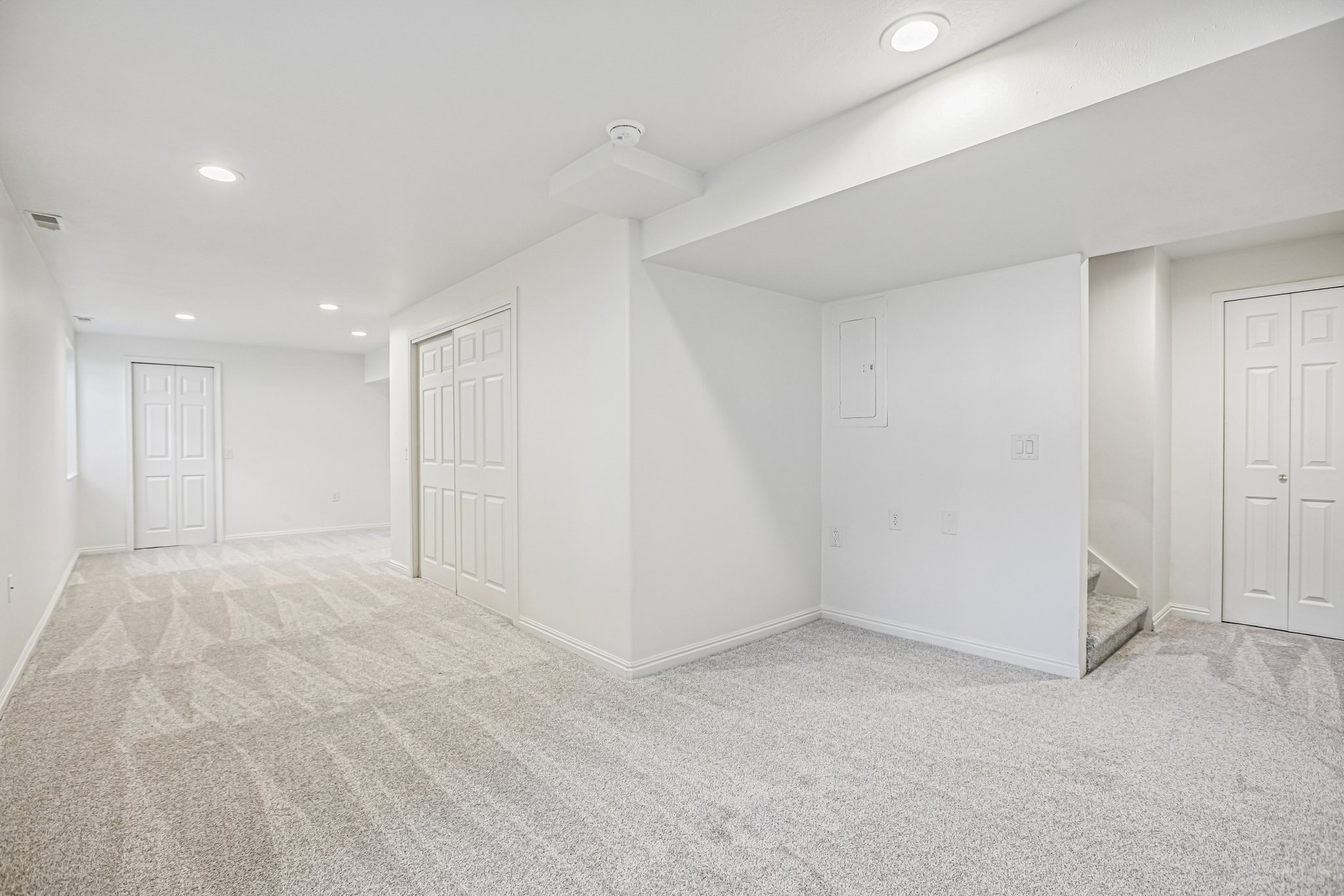 Spacious room featuring light-toned patterned carpeting and recessed ceiling lighting