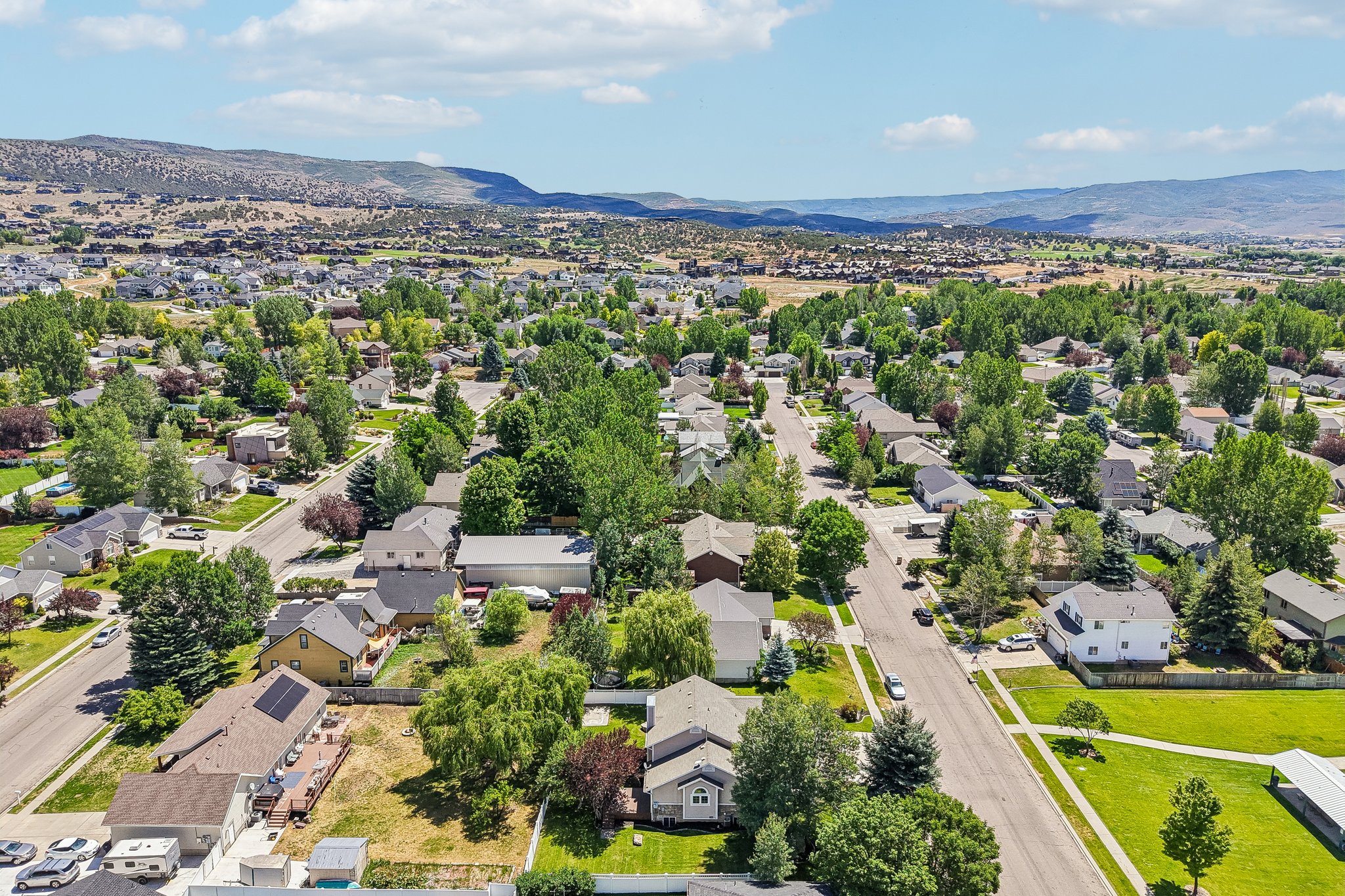 Aerial perspective of a residential community featuring numerous single-family homes, mature trees, and paved streets