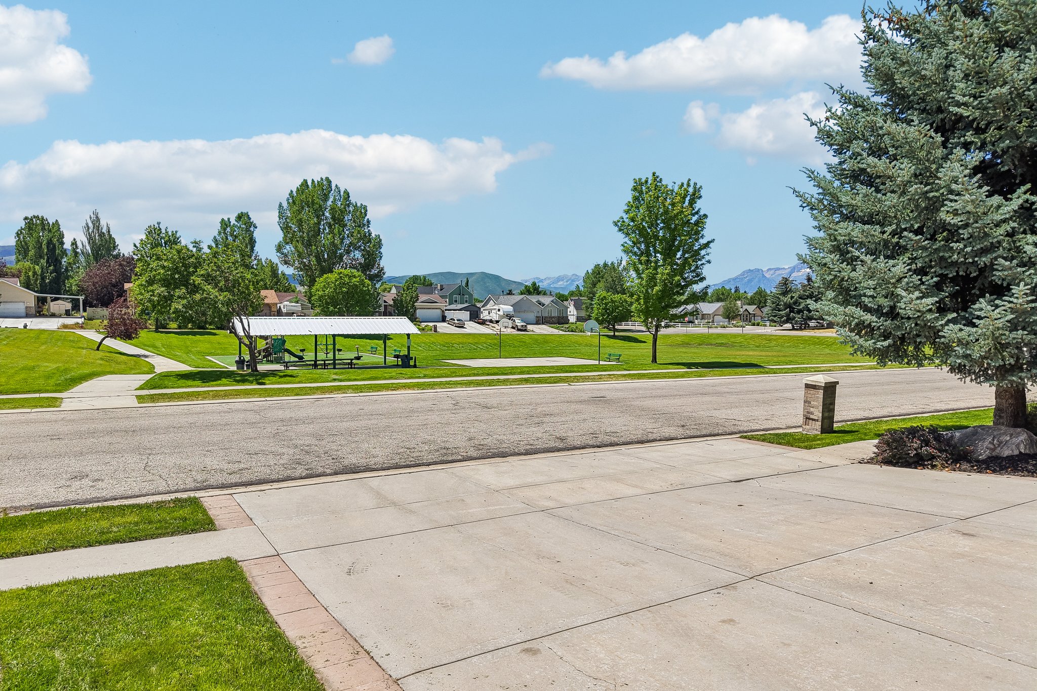 Expansive green space featuring a covered pavilion, playground equipment, and an open court area