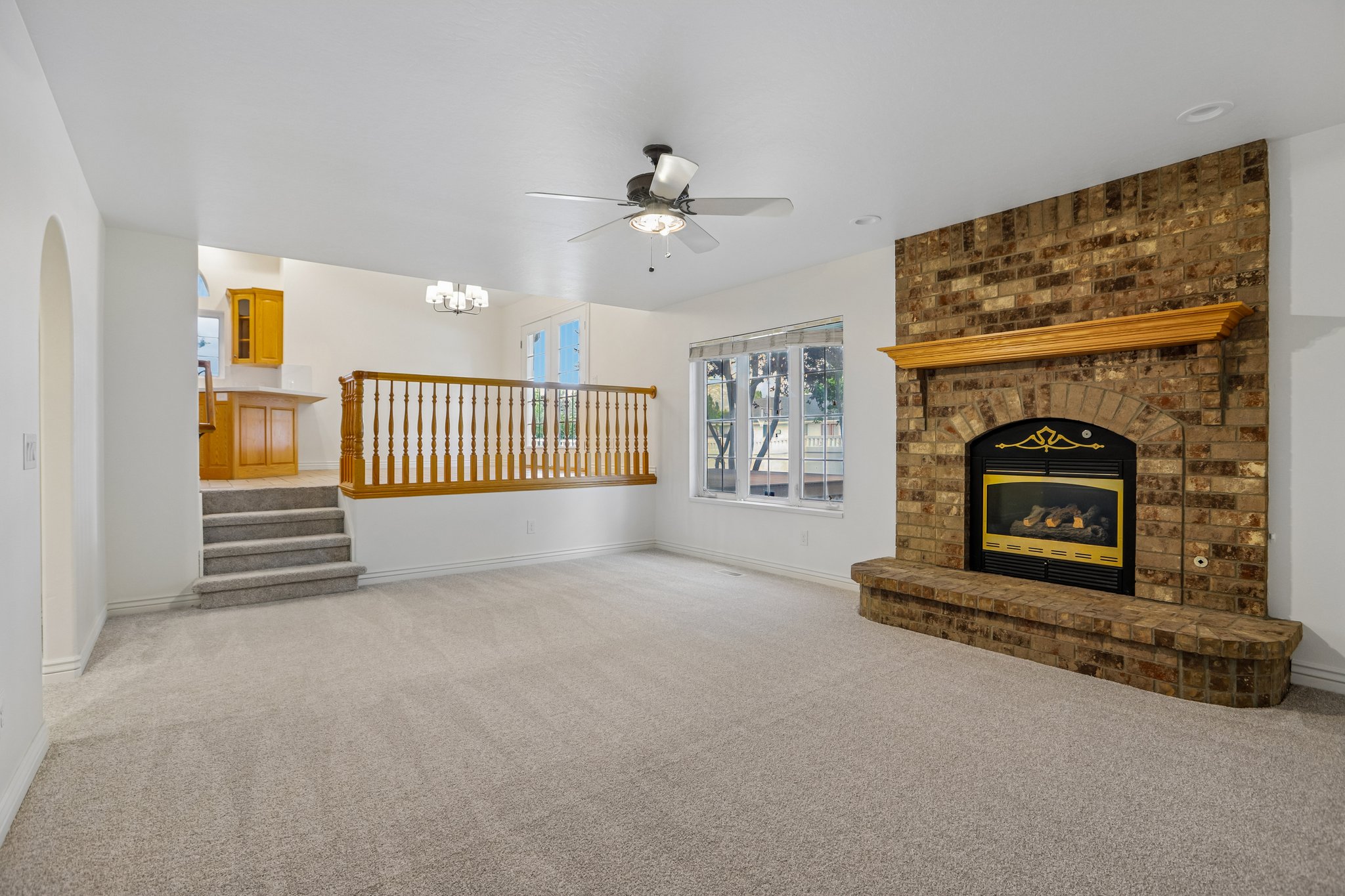 Spacious living area featuring a brick-faced fireplace with hearth and wood mantel
