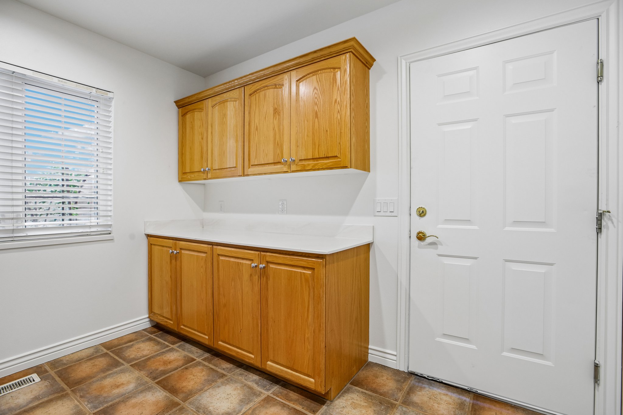 Cabinetry featuring light wood finishes, white countertops, and tile flooring