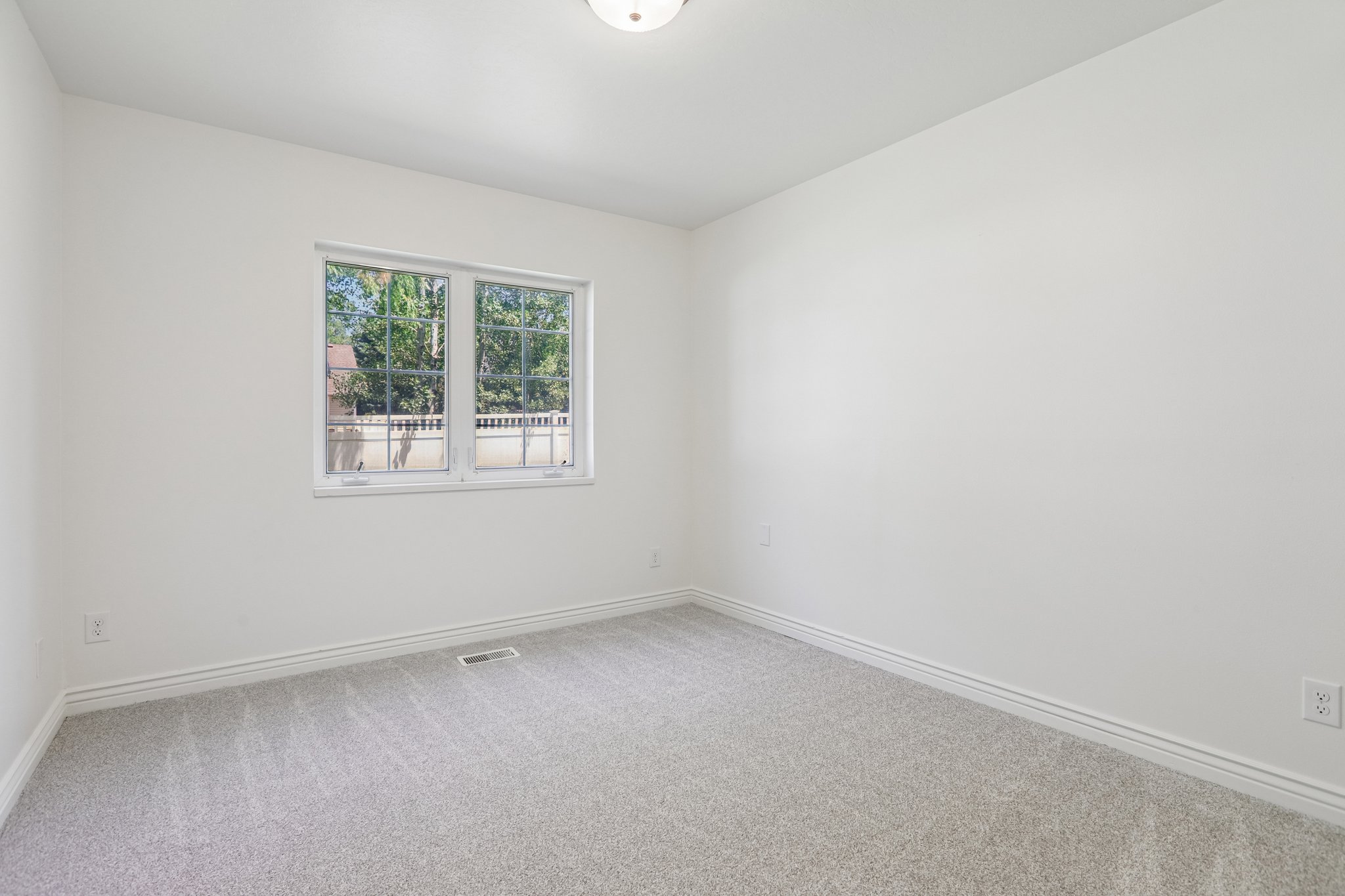 Bright room featuring a double window, neutral wall paint, gray carpeting, and white baseboards