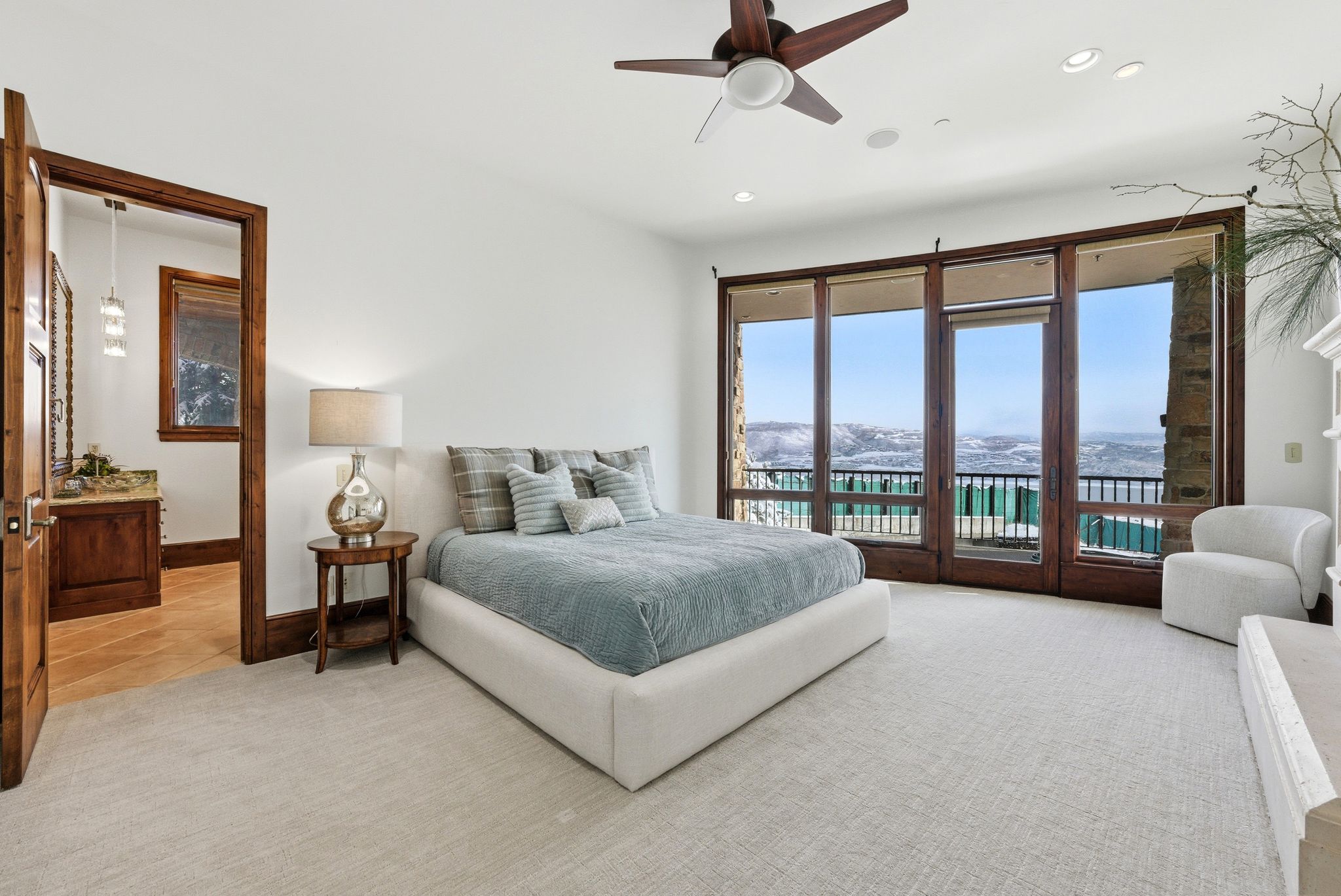 Spacious bedroom featuring a full wall of floor-to-ceiling glass doors, a wood-finish ceiling fan, and recessed lighting