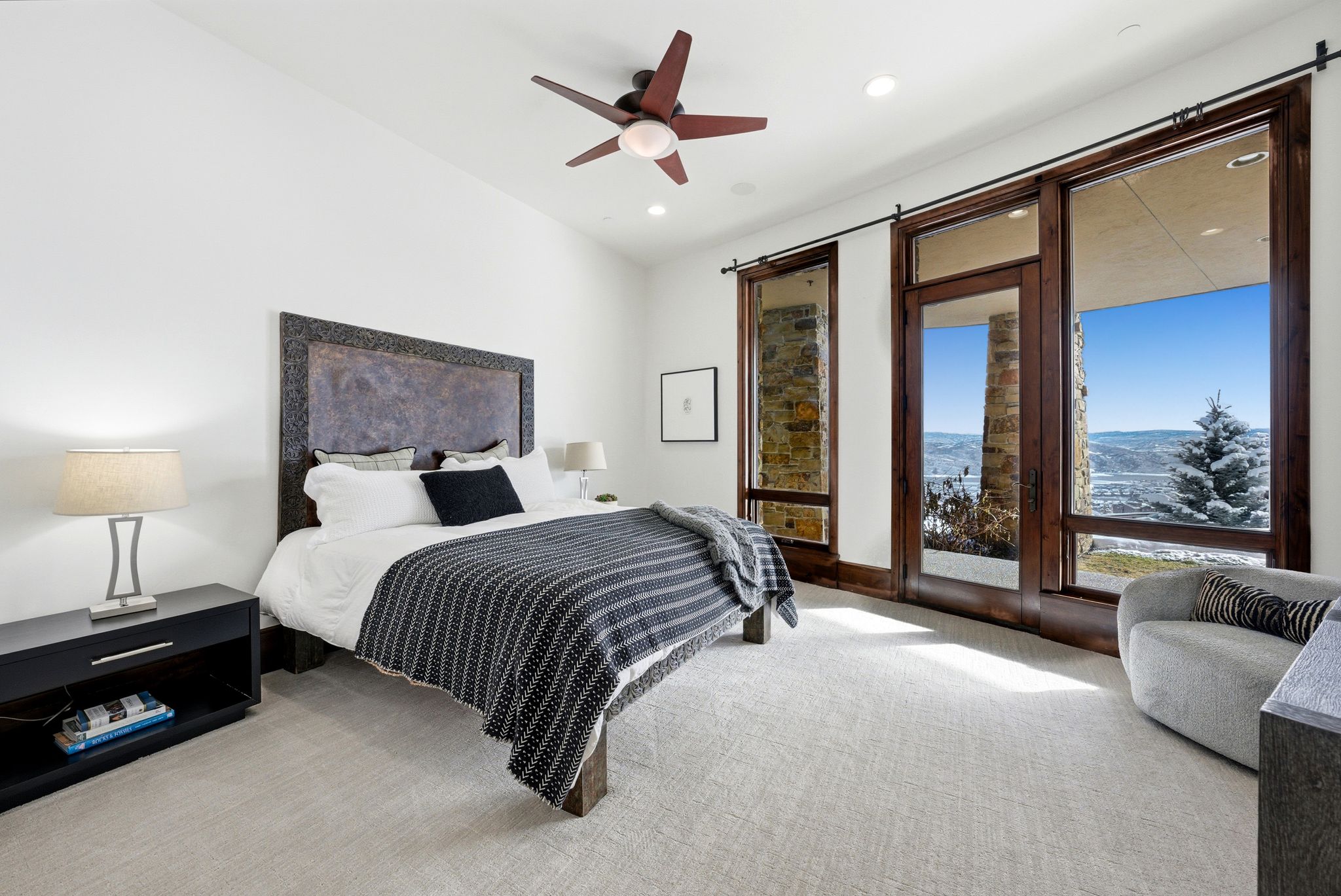 Bedroom featuring a vaulted ceiling with a ceiling fan, wall-to-wall carpeting, and floor-to-ceiling windows with dark wood frames