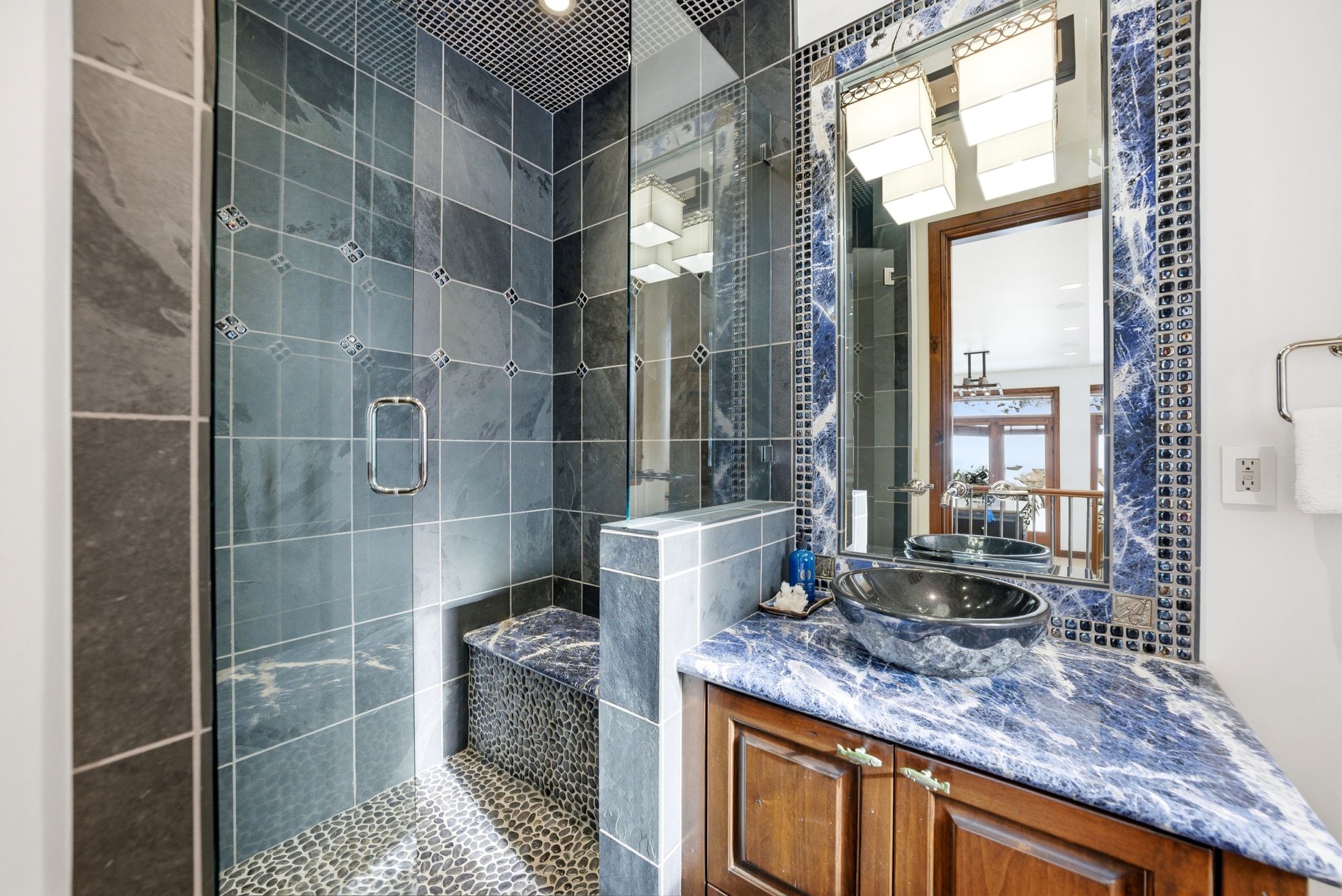Bathroom featuring a glass-enclosed shower with pebble flooring and built-in bench
