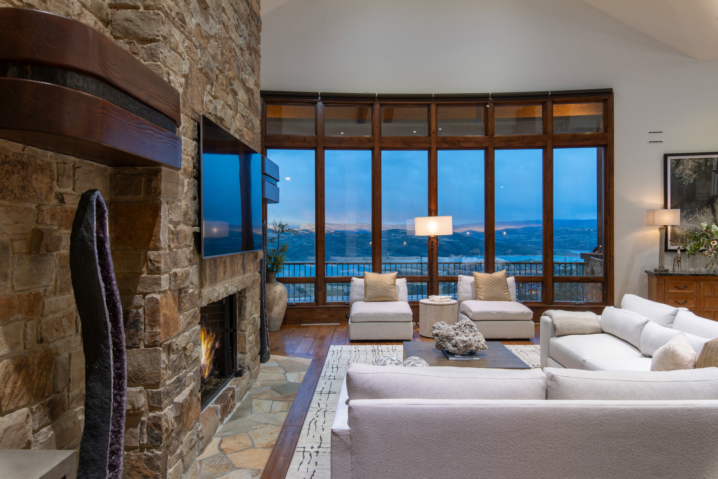 Spacious living area featuring a floor-to-ceiling stone fireplace with a built-in mantel, a large media screen, and flagstone hearth