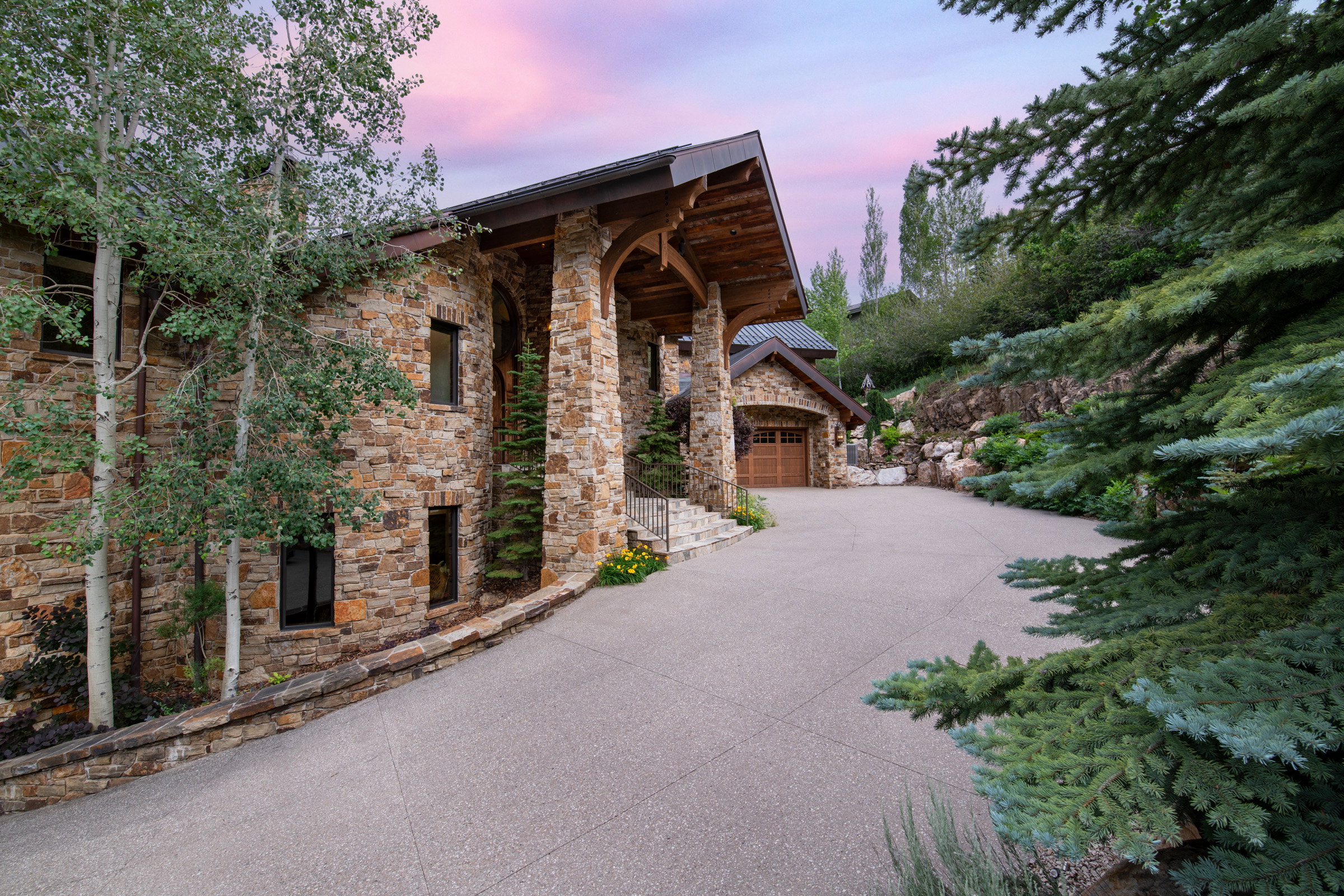 Stone-clad exterior featuring a prominent covered entry with exposed beam details