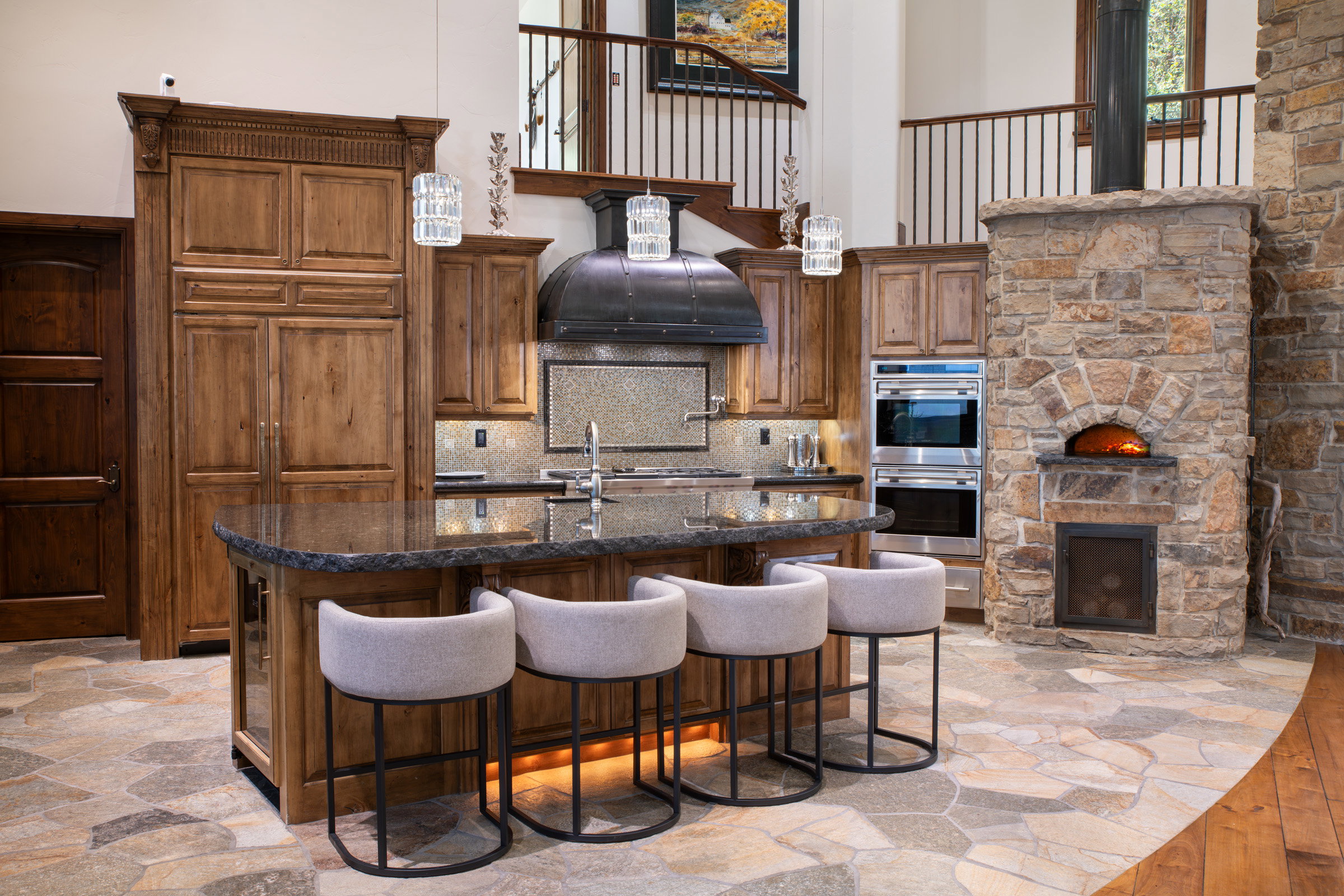 Gourmet kitchen featuring a large island with granite countertops, custom wood cabinetry, and a stone pizza oven
