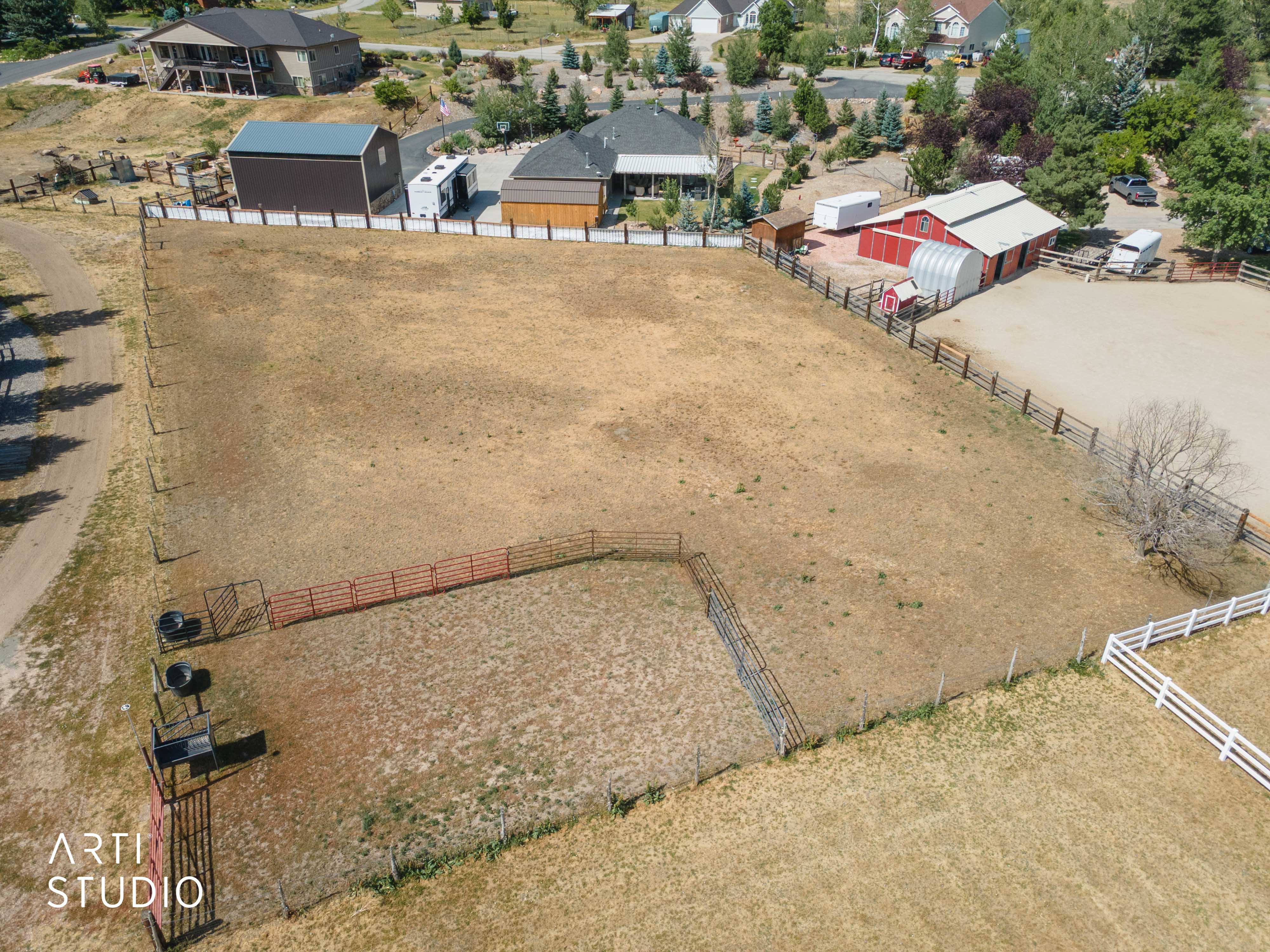 Expansive land parcel with fencing, featuring a barn structure, additional outbuilding, and a dedicated arena area