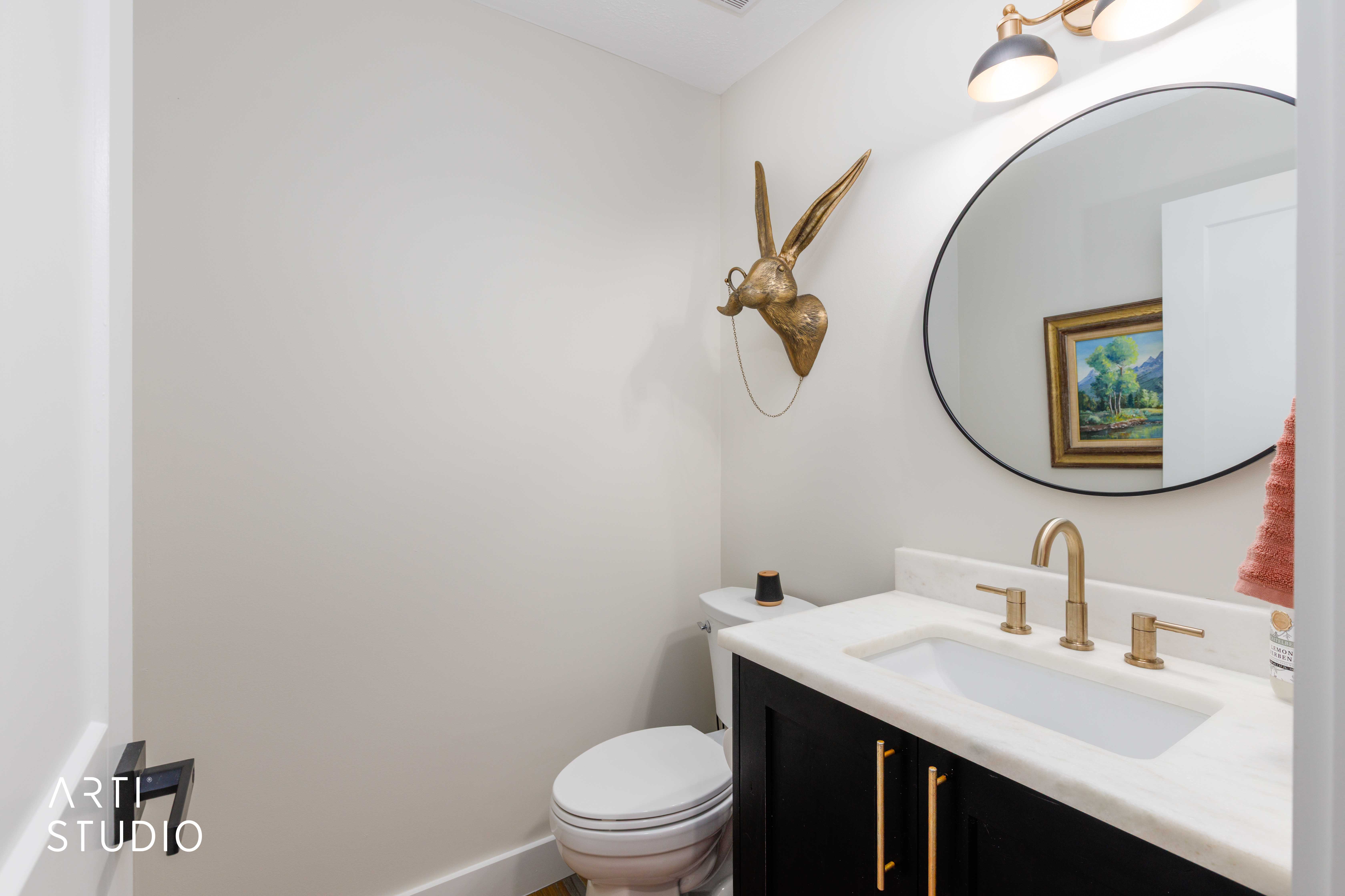 Powder room featuring a black vanity with gold hardware, white countertop, and gold faucet