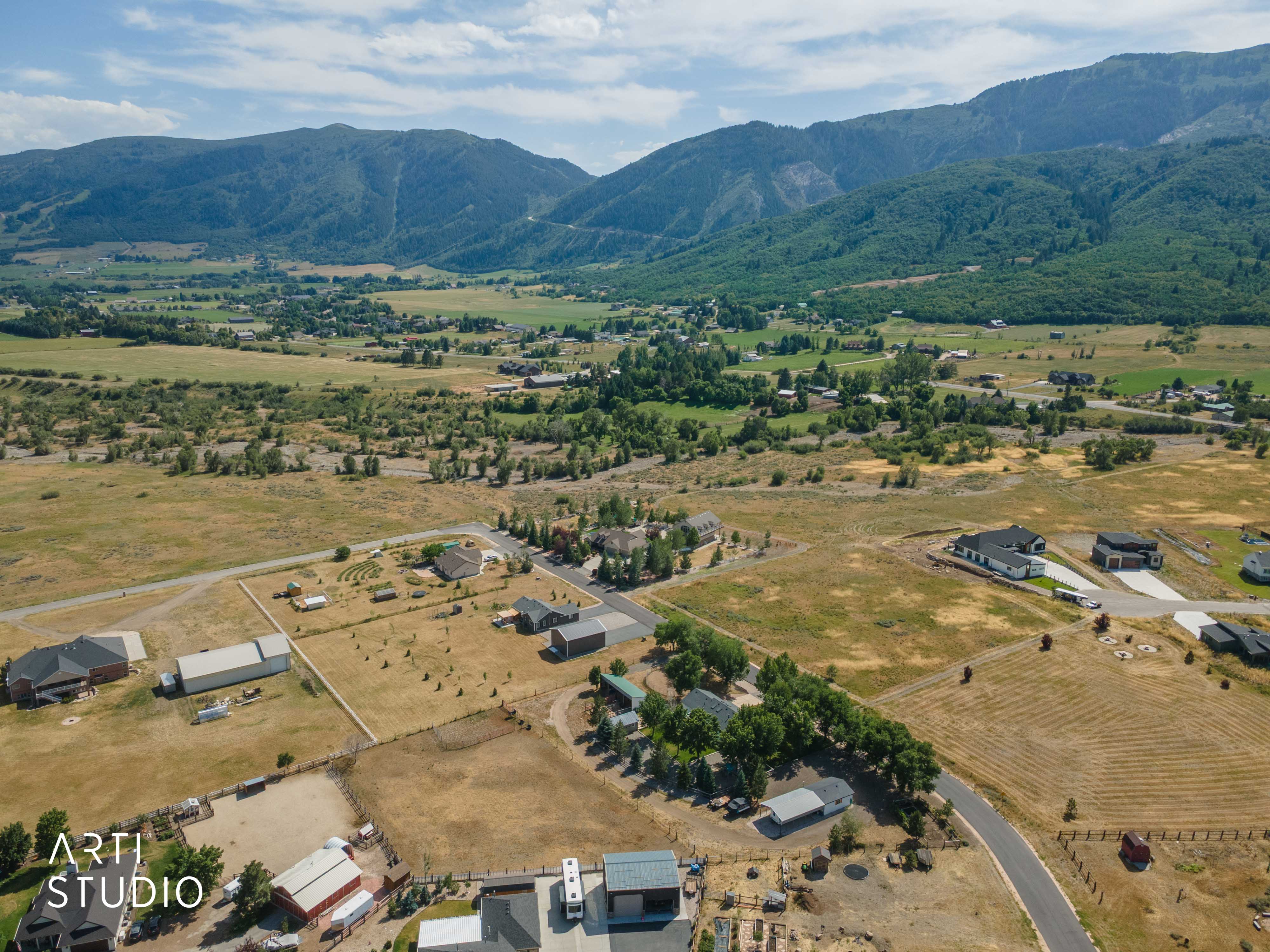 Expansive rural landscape featuring a mountainous backdrop and scattered residential properties