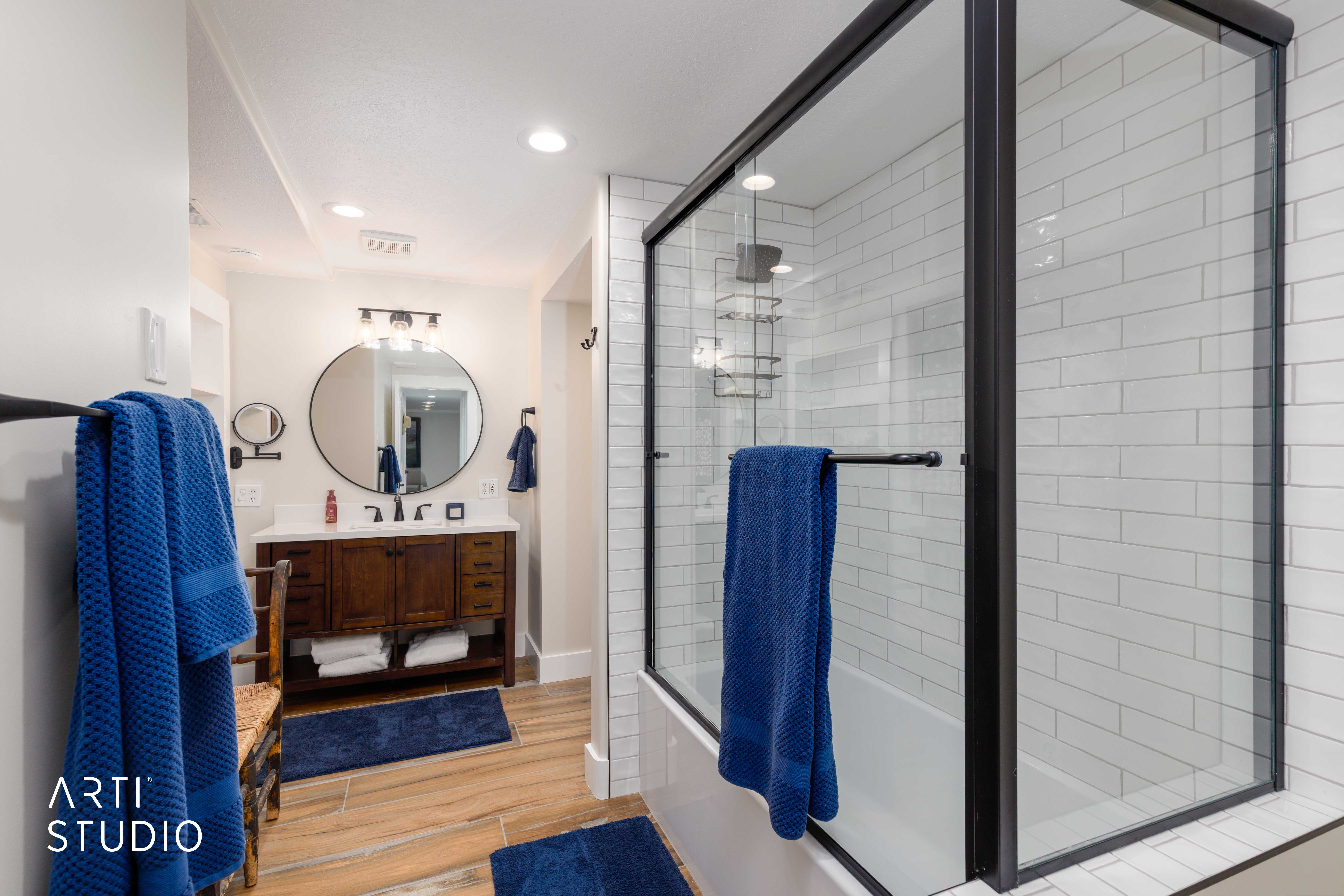 Modern bathroom featuring a wood-finish vanity with a white countertop and a circular mirror