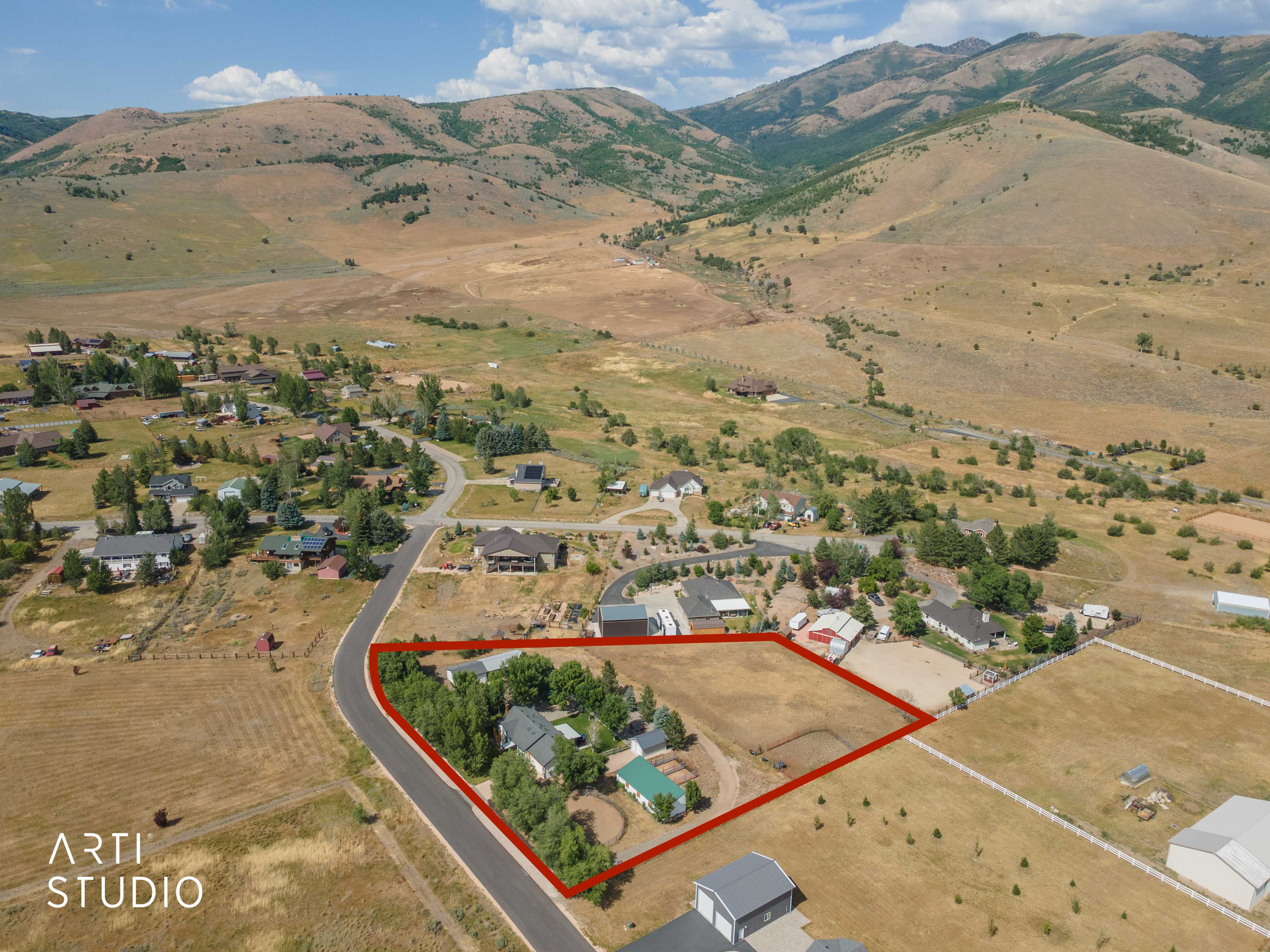 Expansive property parcel highlighted by a red boundary, featuring a paved road frontage, mature trees, and open land