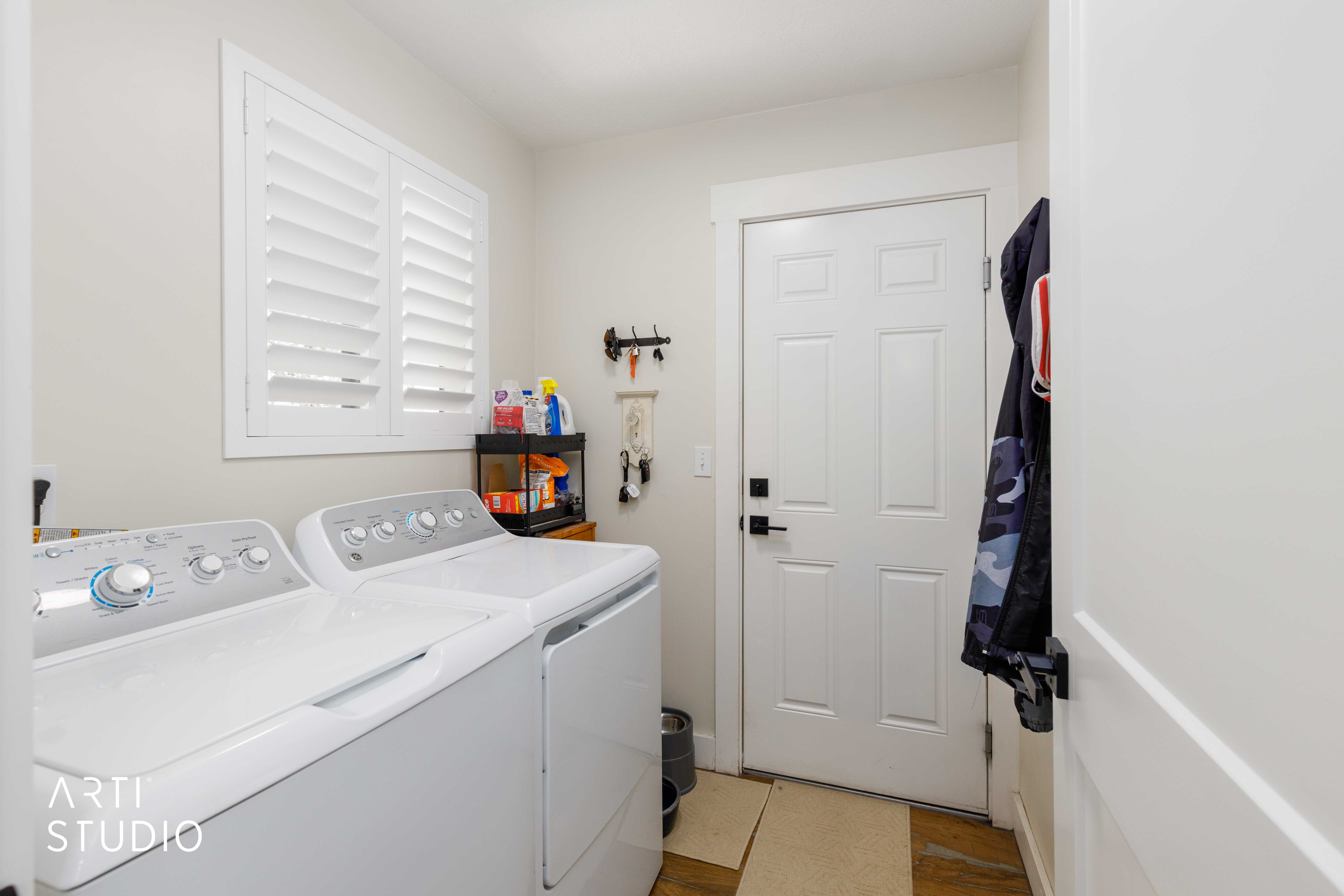 Dedicated laundry area featuring wood-finish flooring and a window with white plantation shutters