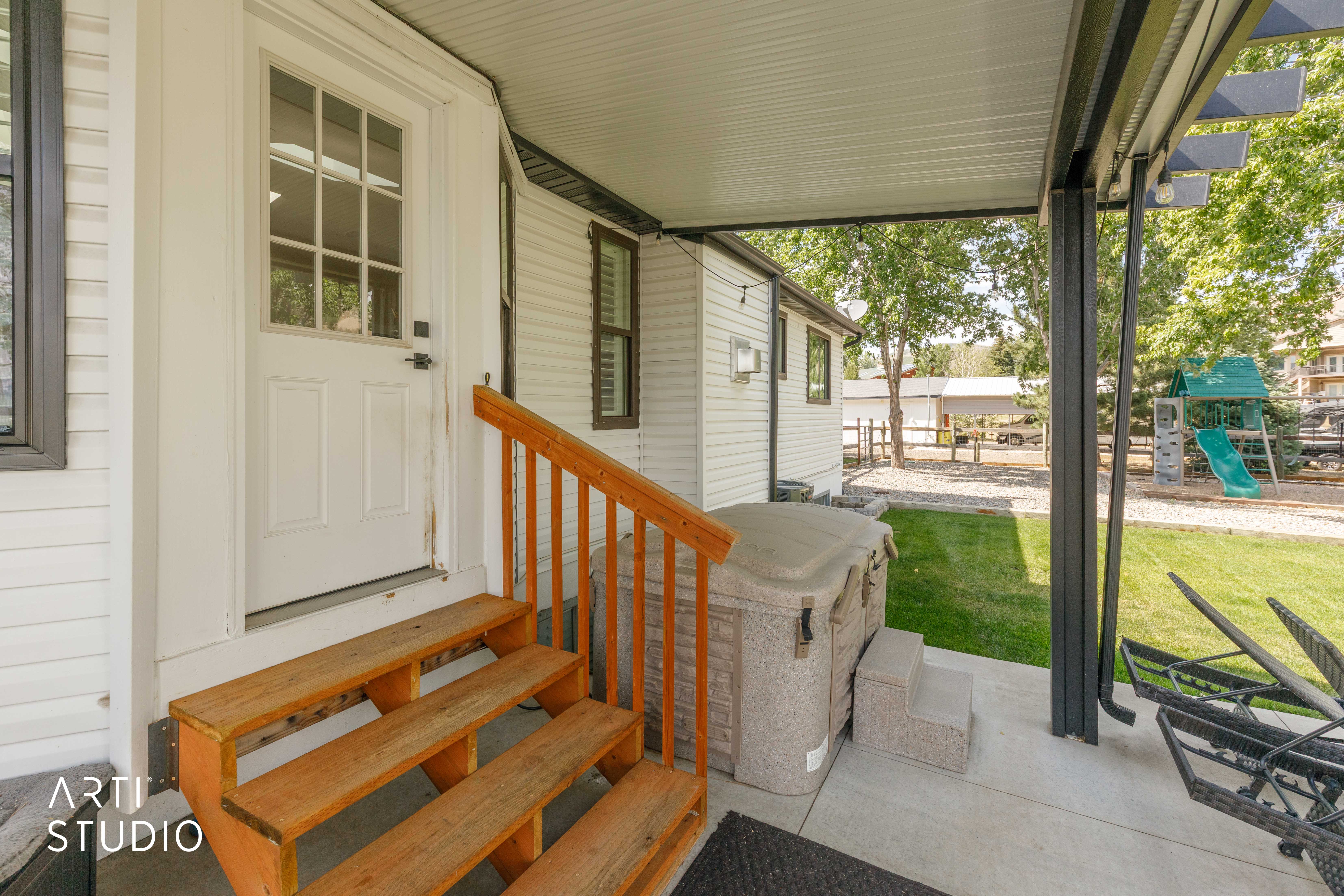 Covered patio featuring a spa, concrete flooring, and a white paneled door with glass inserts