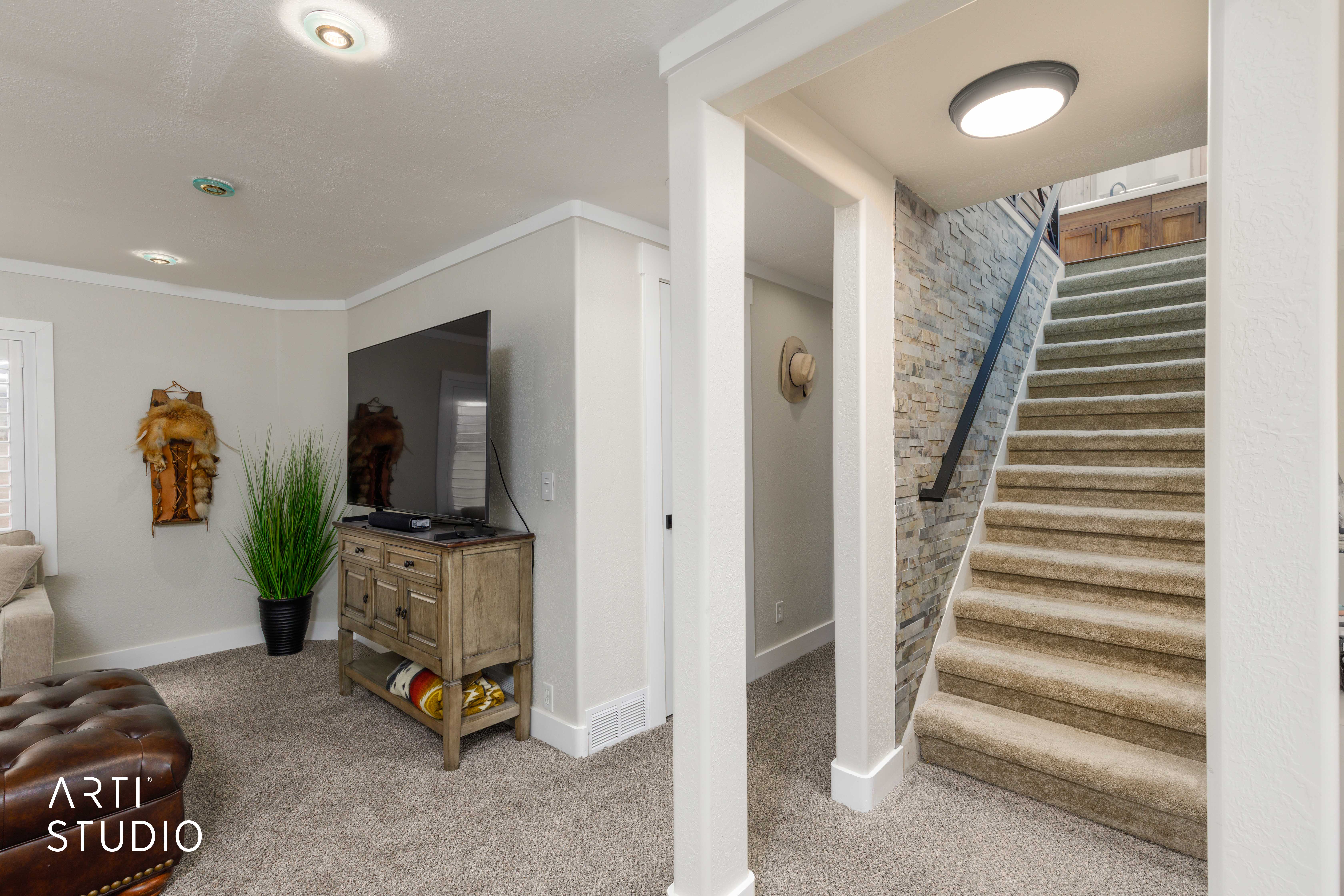 Carpeted staircase with a stone accent wall and black handrail
