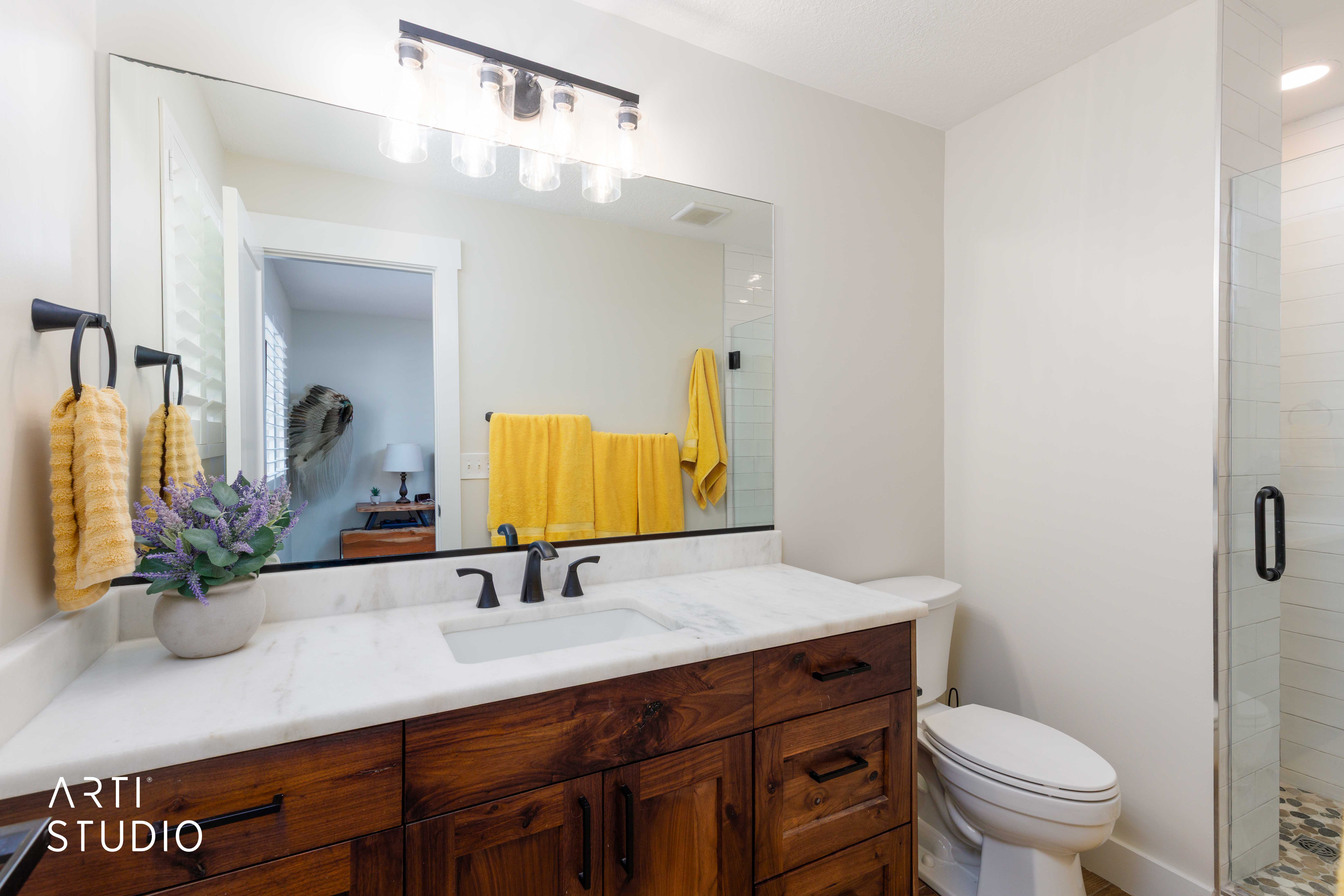 Bathroom vanity featuring a wood-finish cabinet with black hardware, a white countertop, and a rectangular undermount sink with a black faucet