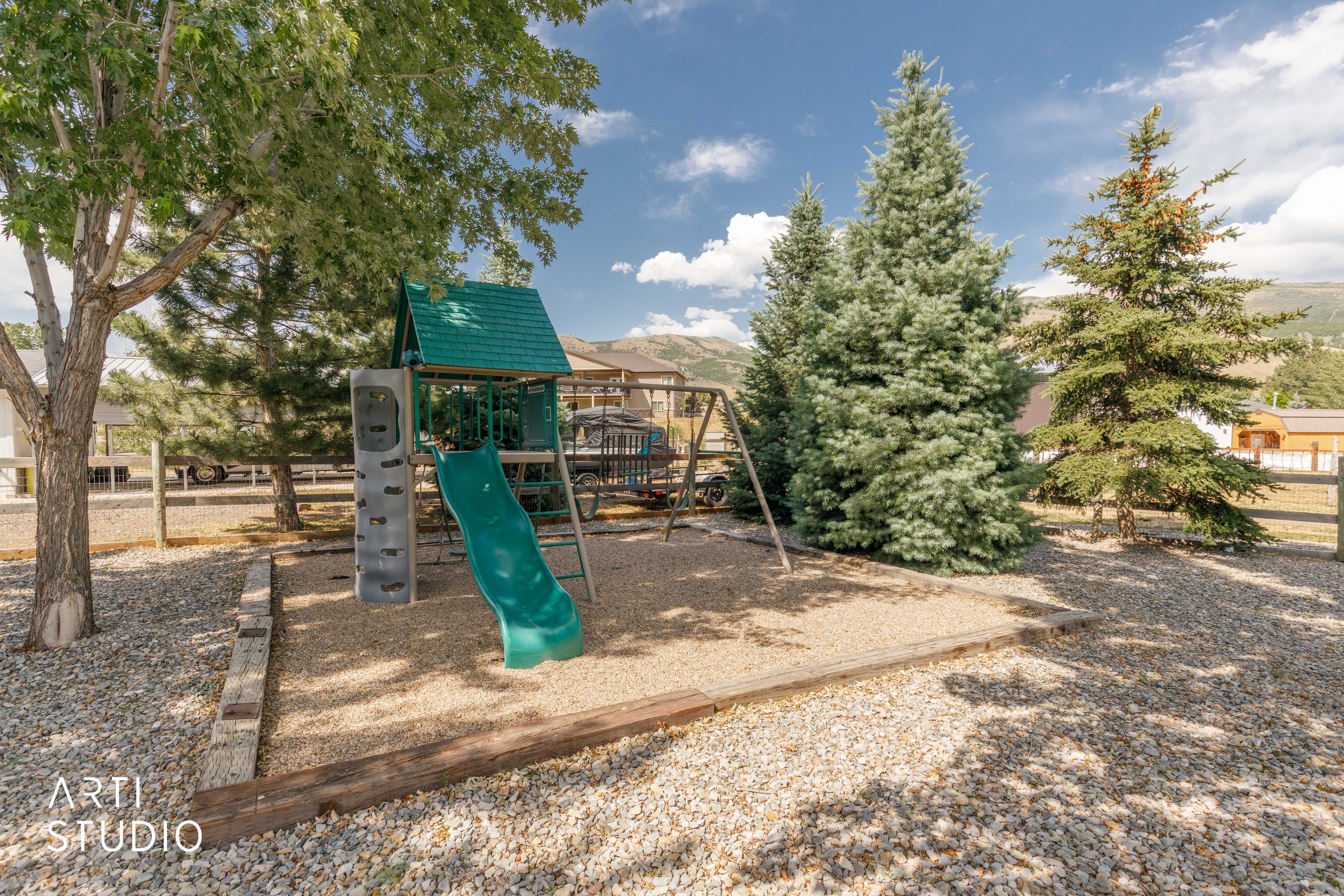 Outdoor play area featuring a swing set, slide, and climbing wall