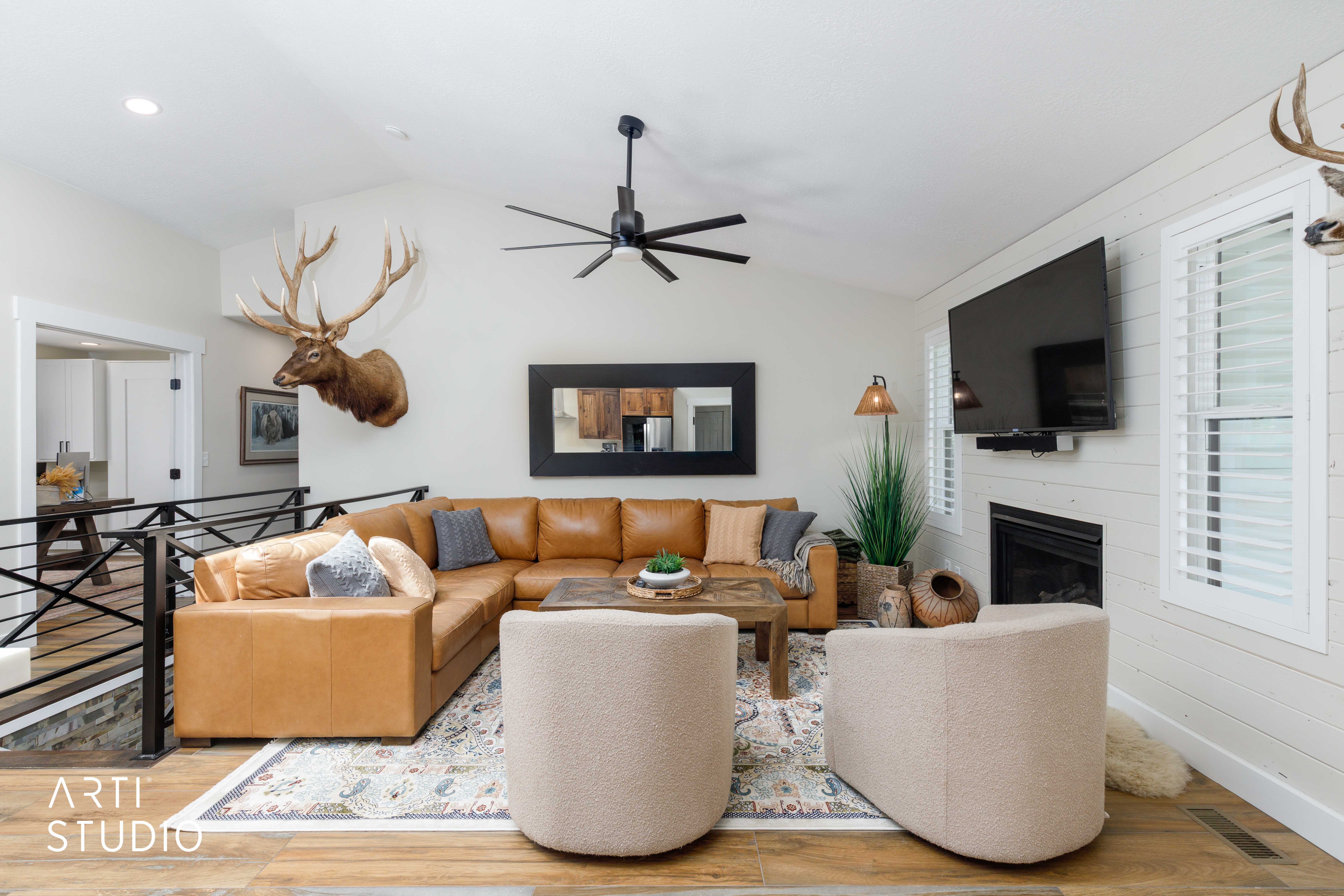 Vaulted ceiling living area featuring a black ceiling fan, wood-finish flooring, and a fireplace with a shiplap surround