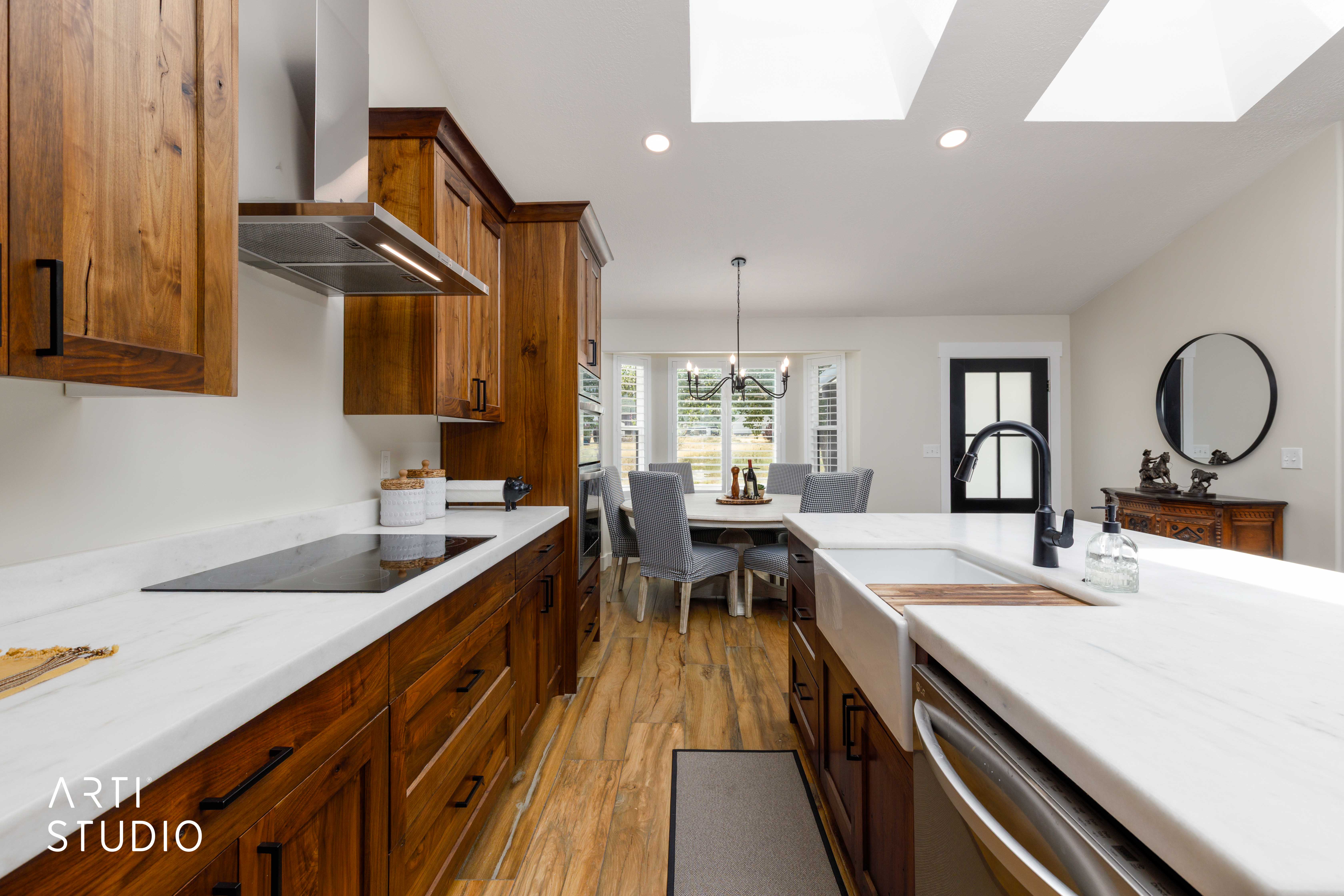 Well-appointed kitchen featuring hardwood cabinetry, white countertops, a built-in cooktop, and a stainless steel range hood
