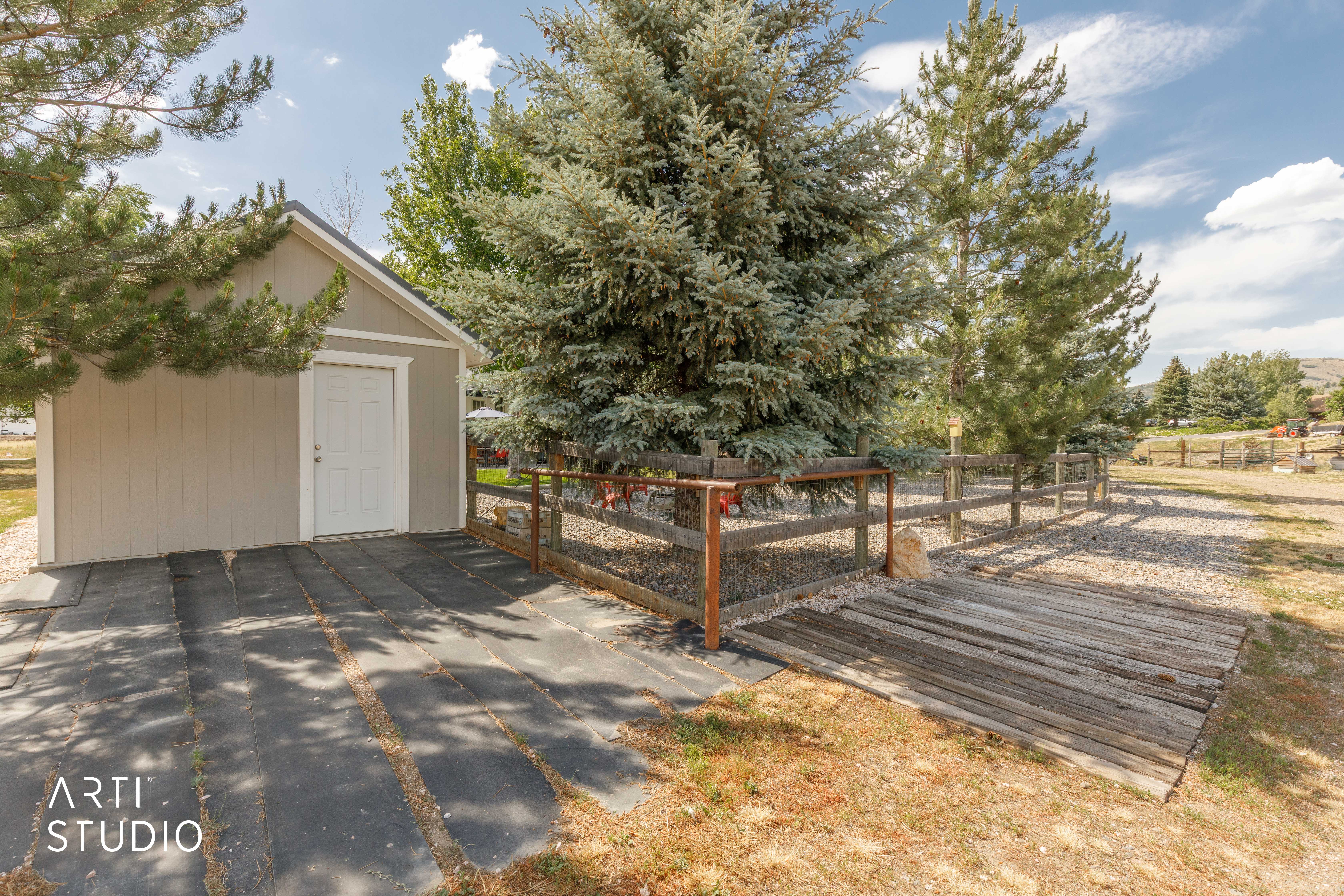 Freestanding shed with a gabled roof and light gray siding