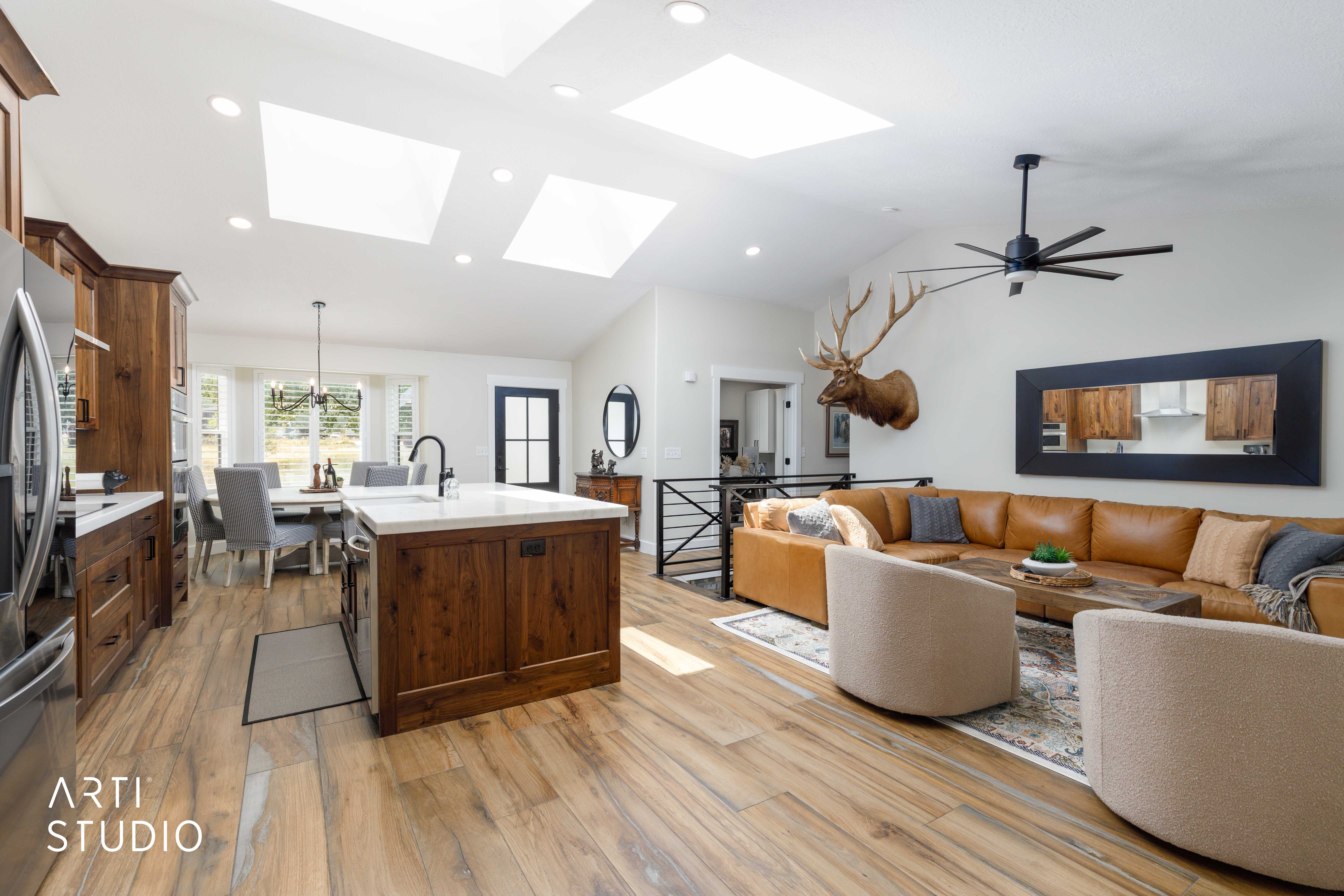 Open-concept living area featuring high vaulted ceilings, multiple skylights, and wood-finish flooring
