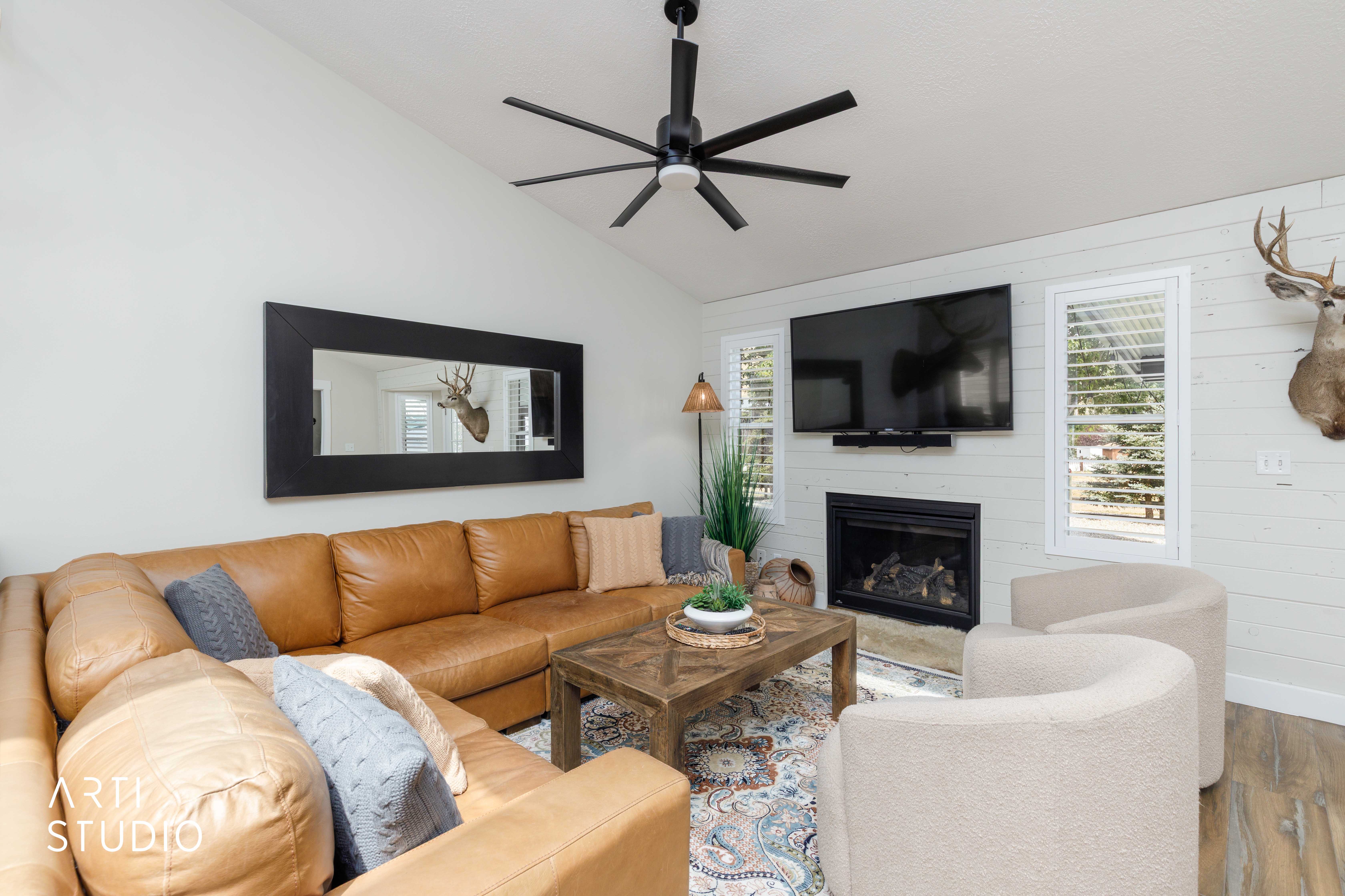 Vaulted ceiling featuring a contemporary ceiling fan, shiplap accent wall, built-in fireplace, and wood-finish flooring
