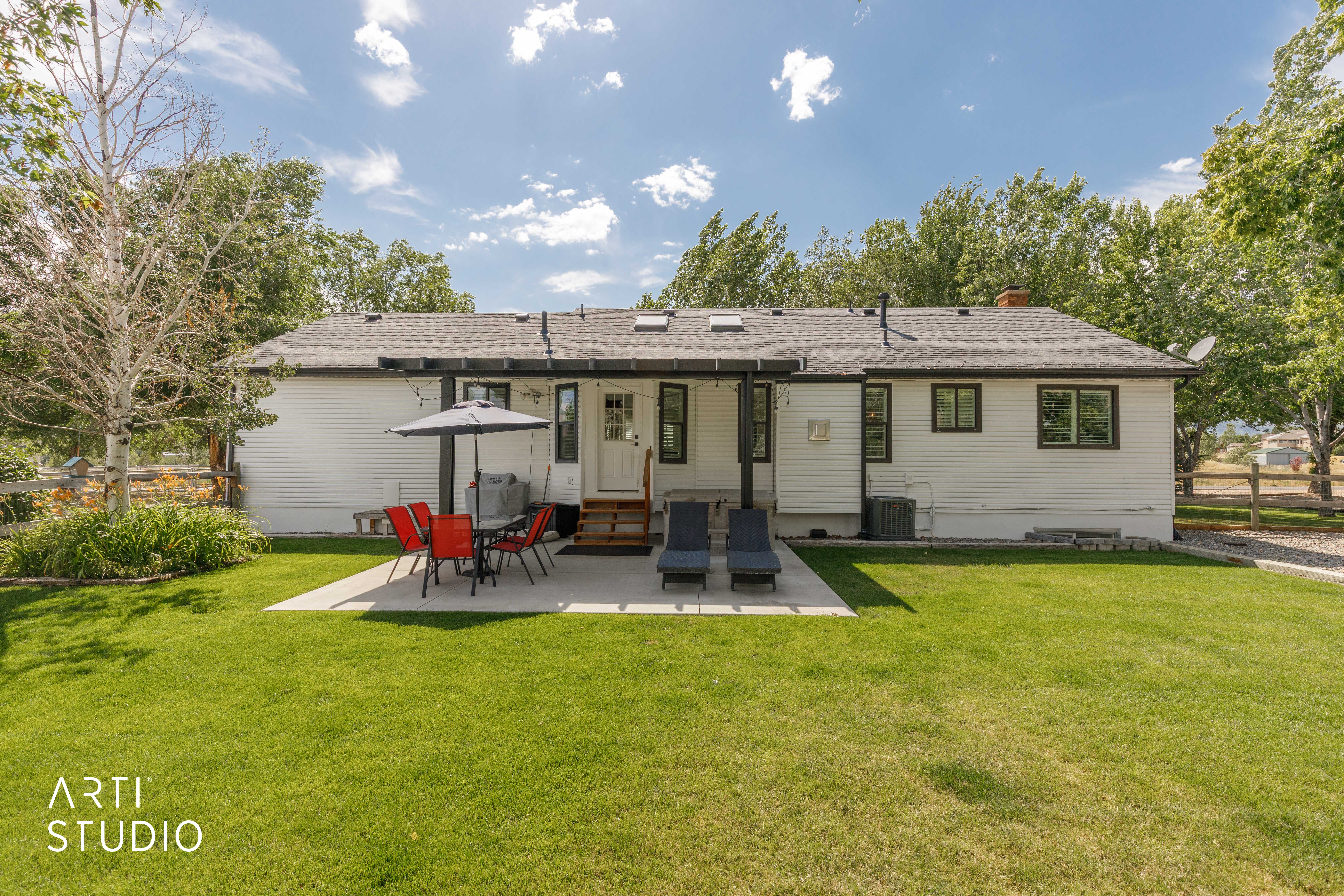 Expansive backyard with a manicured lawn, concrete patio, and mature trees