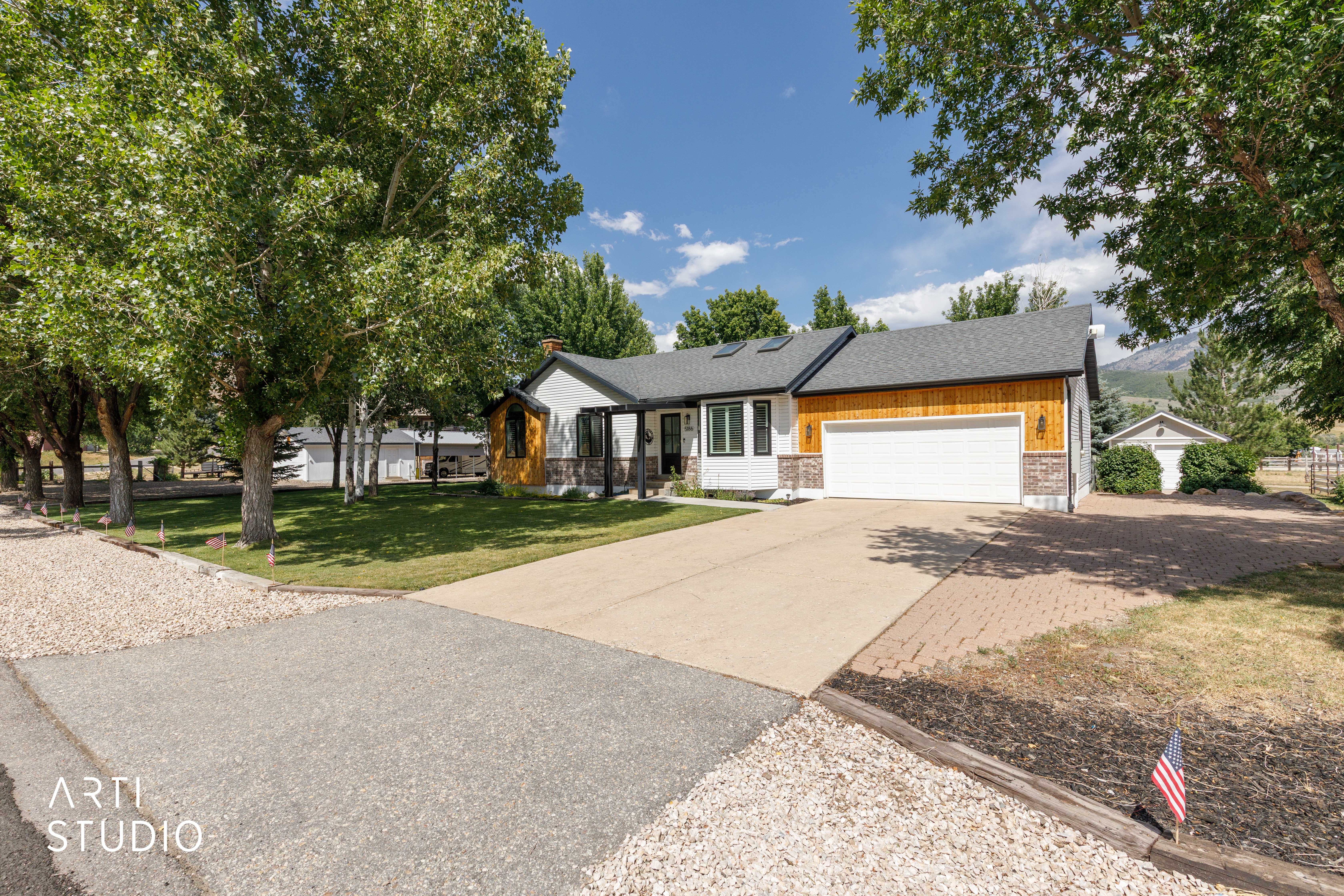 Ranch-style residence featuring a white facade, wood-finish siding, and stone accents