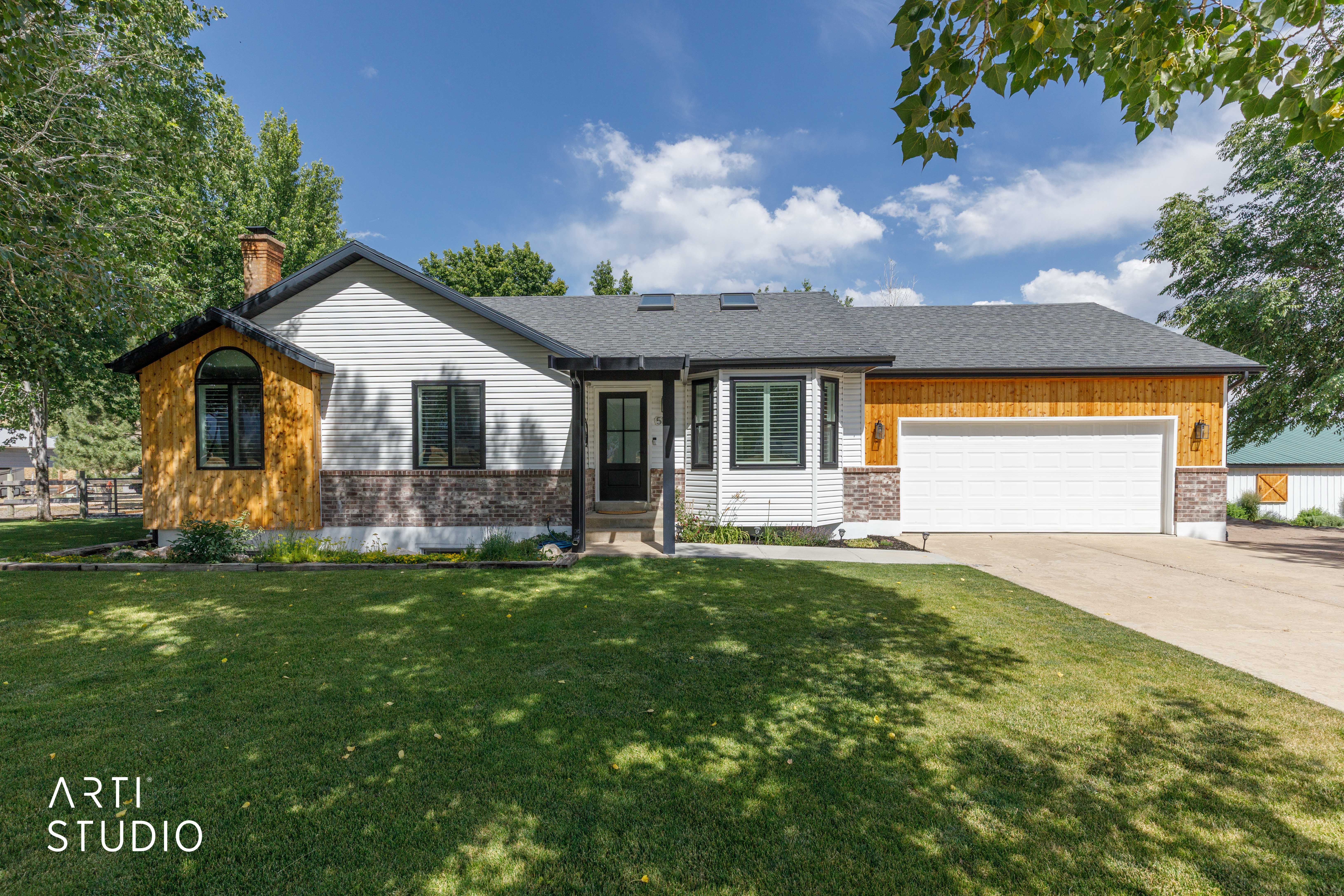 Single-story residence featuring white siding, stone veneer accents, and wood-finish paneling