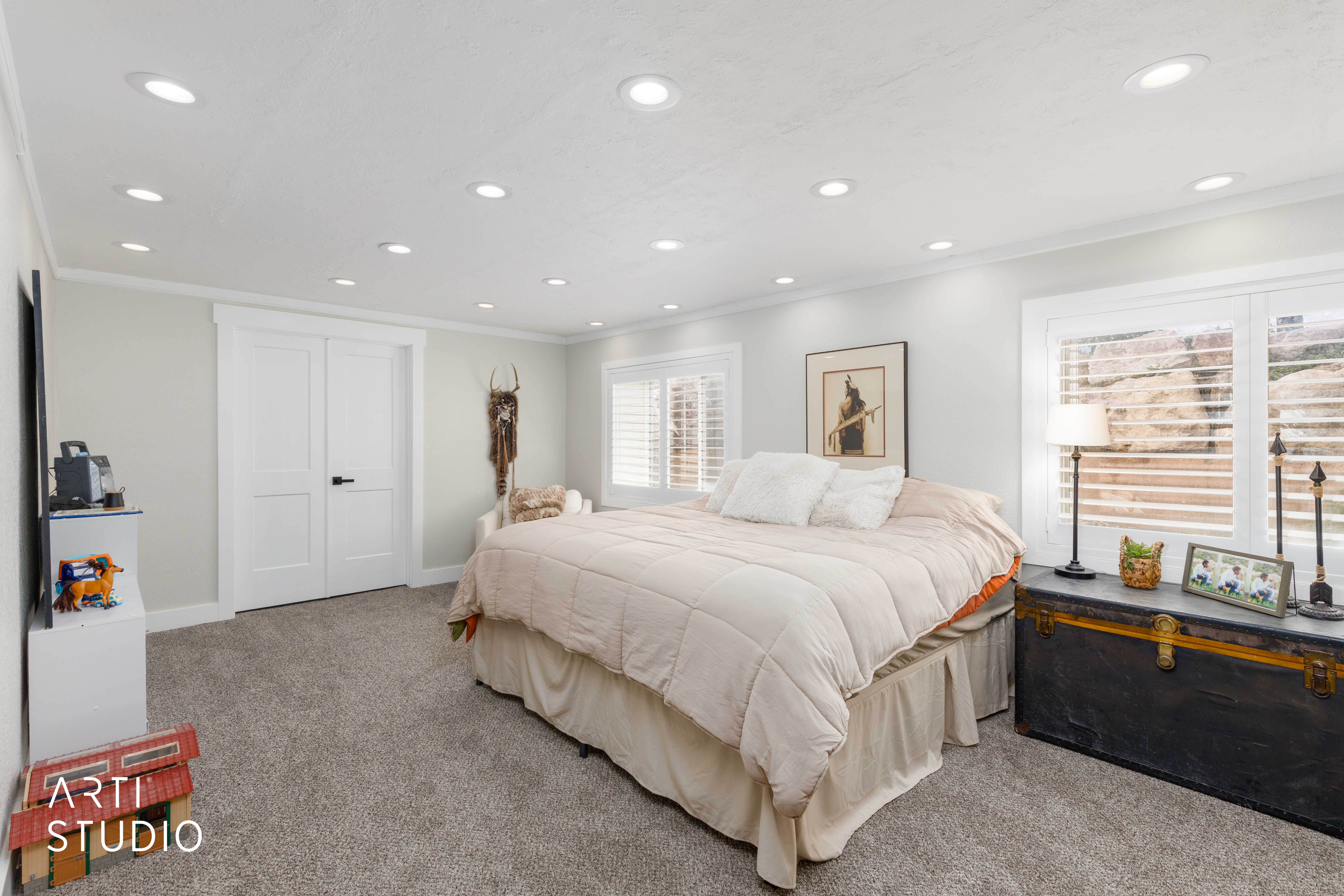 Carpeted room featuring recessed lighting, a pair of white paneled doors, and two windows with white plantation shutters
