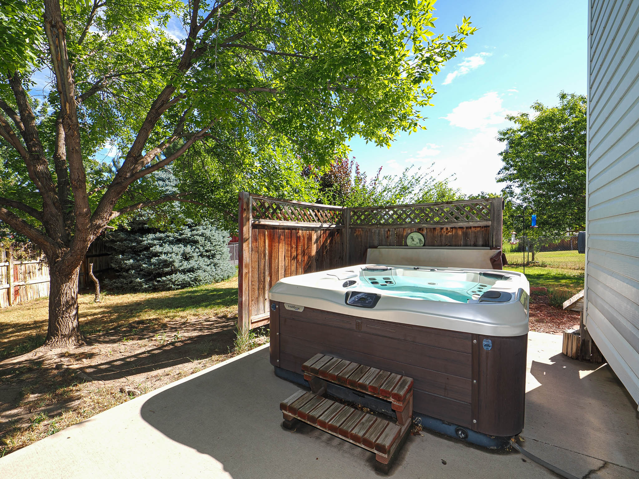 Outdoor spa with wood-finish siding situated on a concrete patio