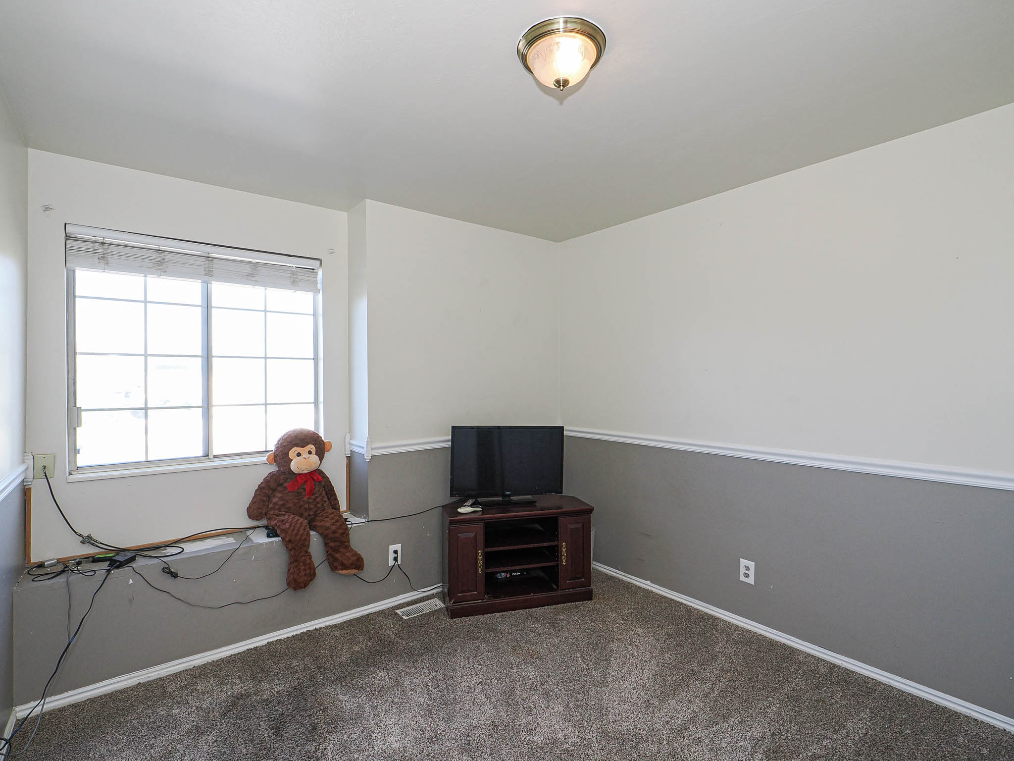 Carpeted room with a multi-pane window, two-tone wall treatment with chair rail molding, and a flush-mount ceiling light fixture