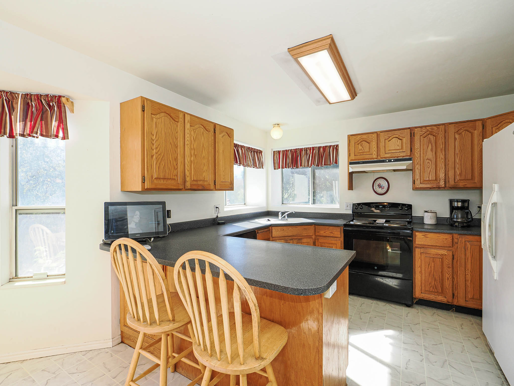Kitchen featuring light wood cabinetry, dark countertops, and a built-in breakfast bar