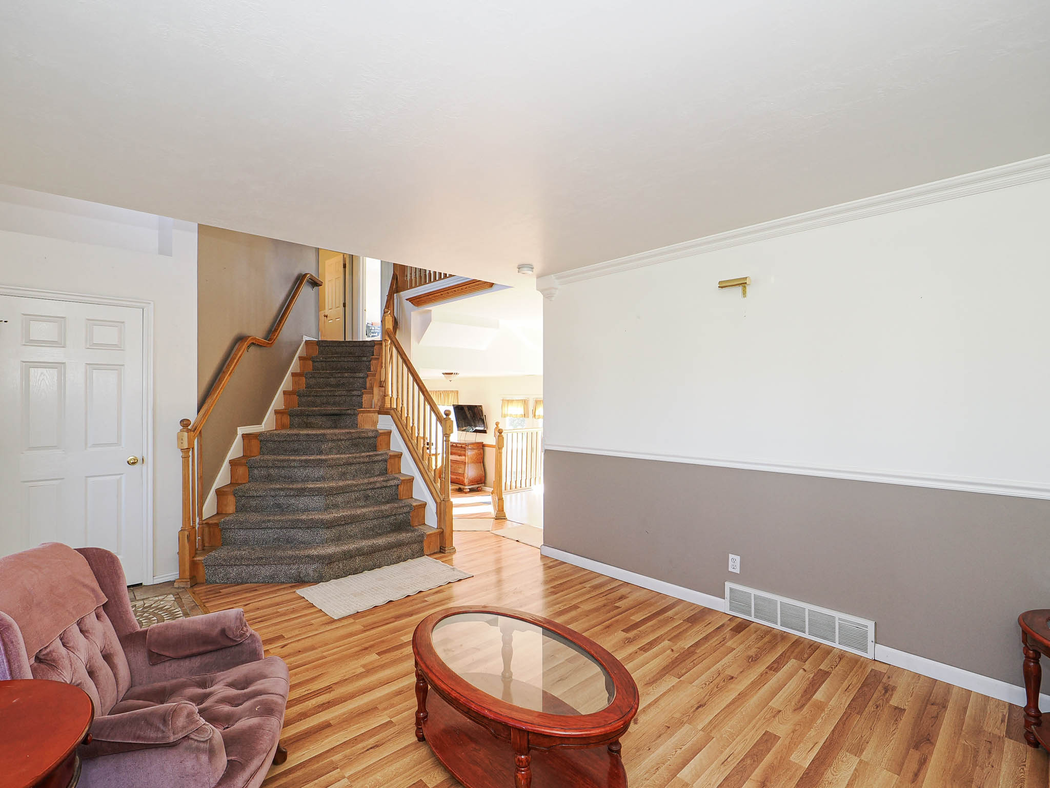 Staircase with wood balusters and carpeted treads, complemented by wood-finish flooring